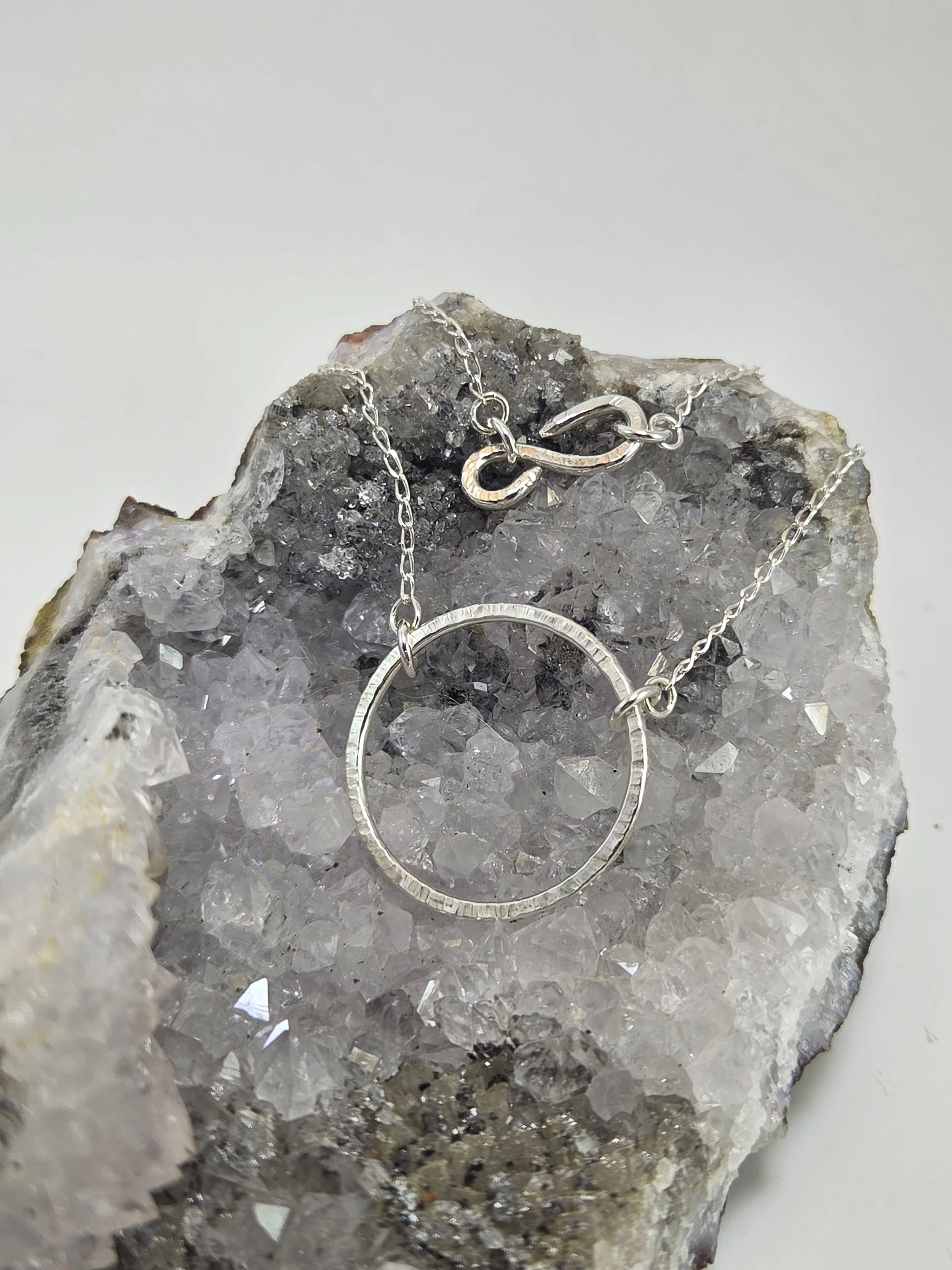 Silver circle necklace pendant draped on a crystal