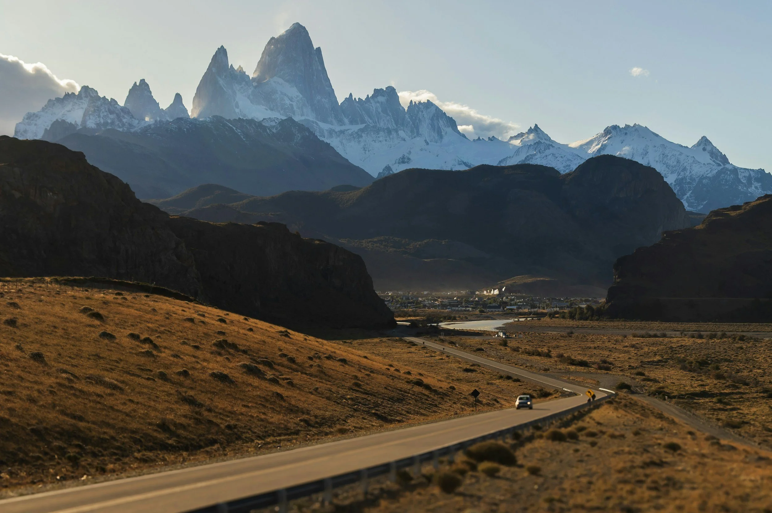 Scenic view of a winding road leading towards distant mountains with snow-capped peaks, under a clear sky. The Horns, Torres del Paine, Patagonia, Chile