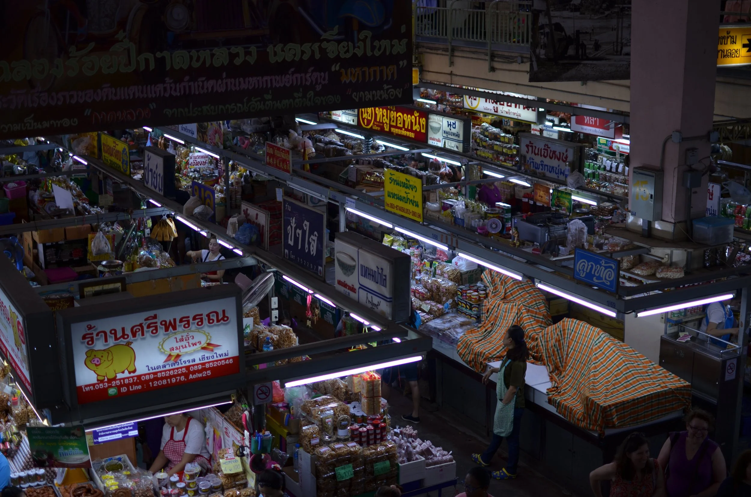 Market stalls with various foods and signs in Thai script.