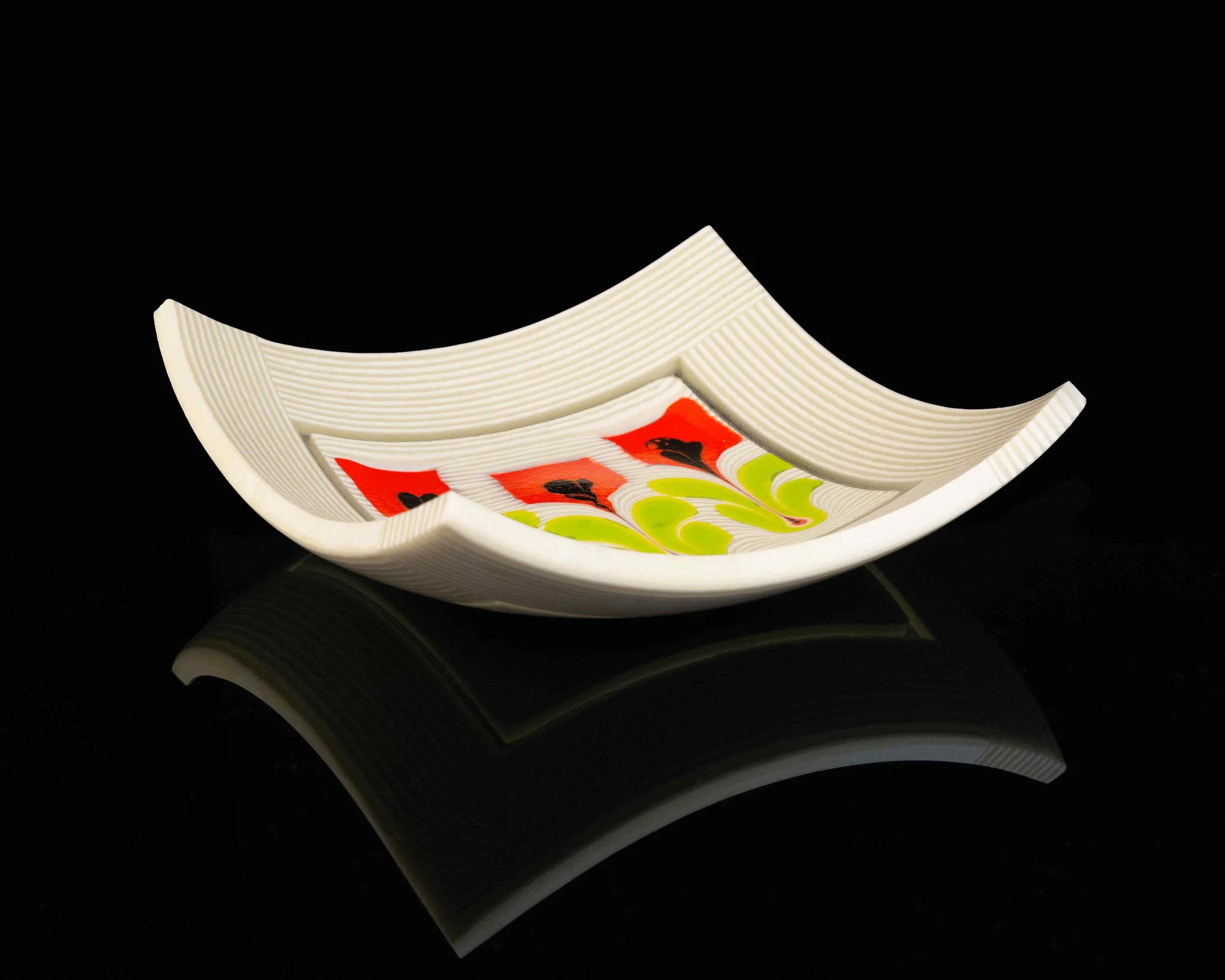 Stack of white plates with colorful bird illustrations, on a black reflective surface.