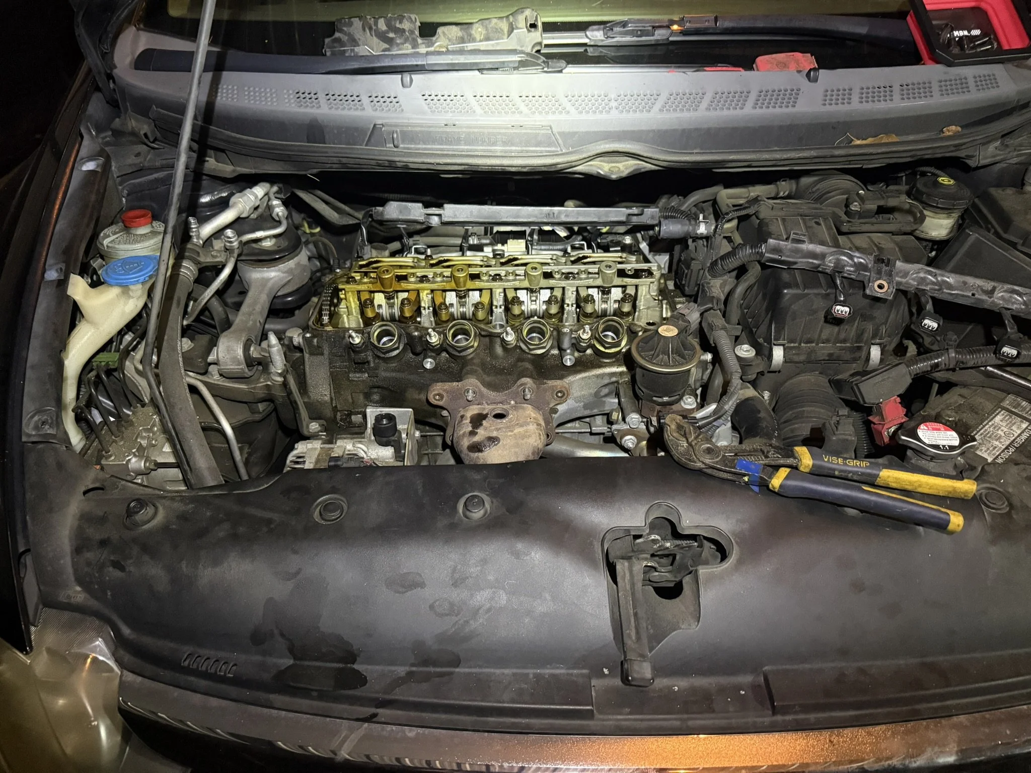 Car engine with valve cover removed, exposing internal components.