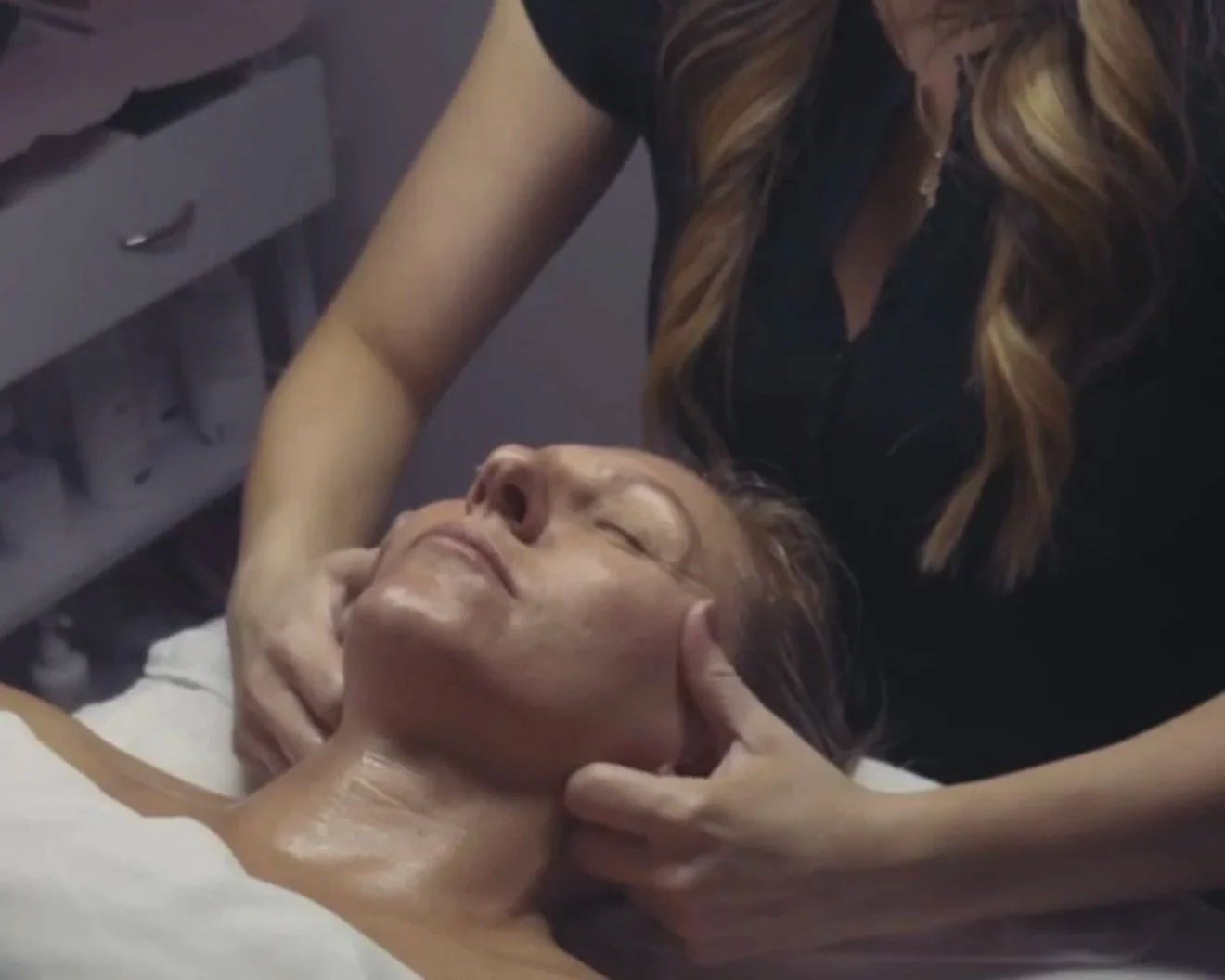 A woman receiving a facial massage in a spa or skincare clinic.