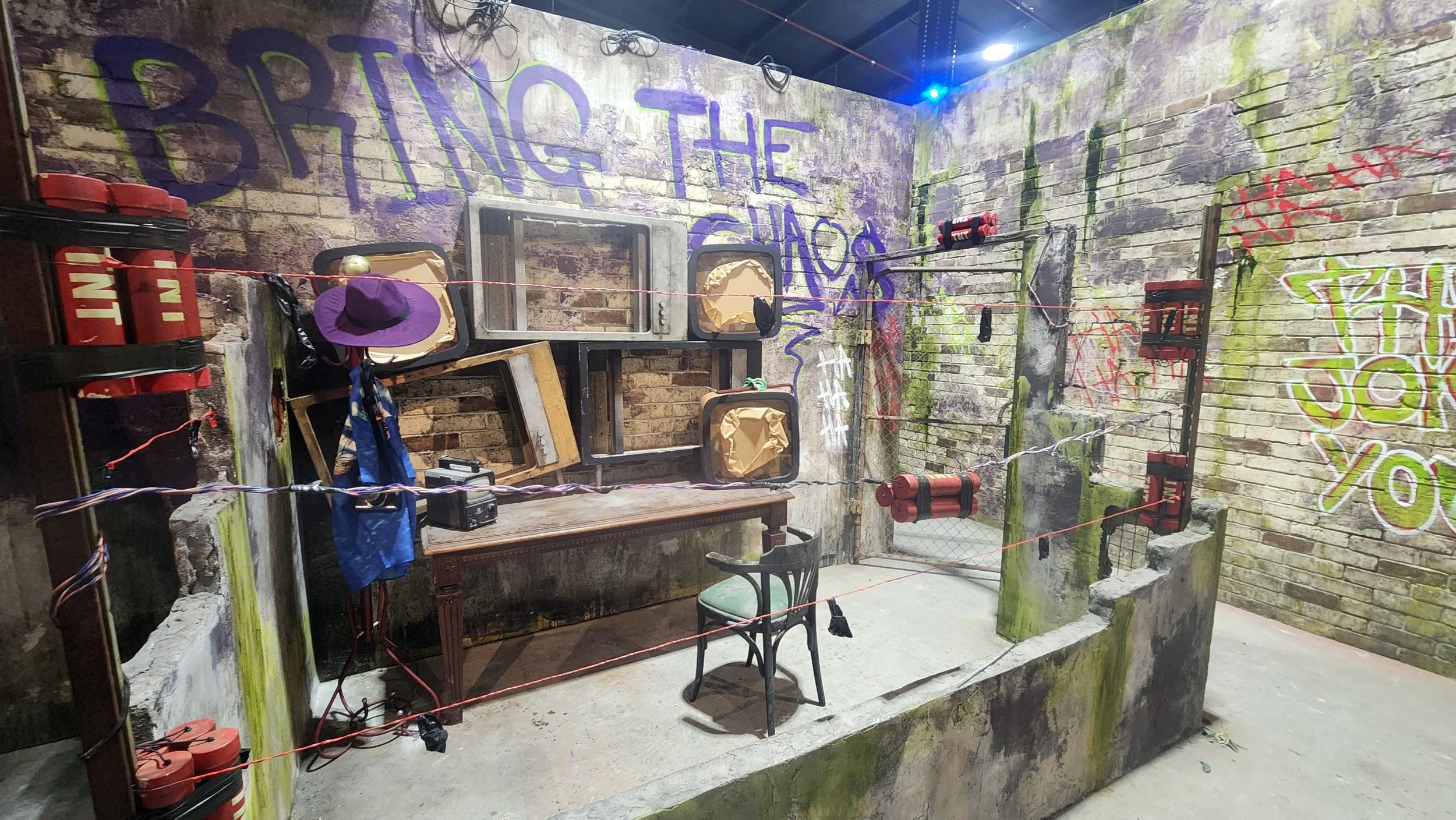 An indoor old-fashioned boxing ring with red corner pads and a rope barrier, against graffiti-covered brick walls with words and designs painted on them.