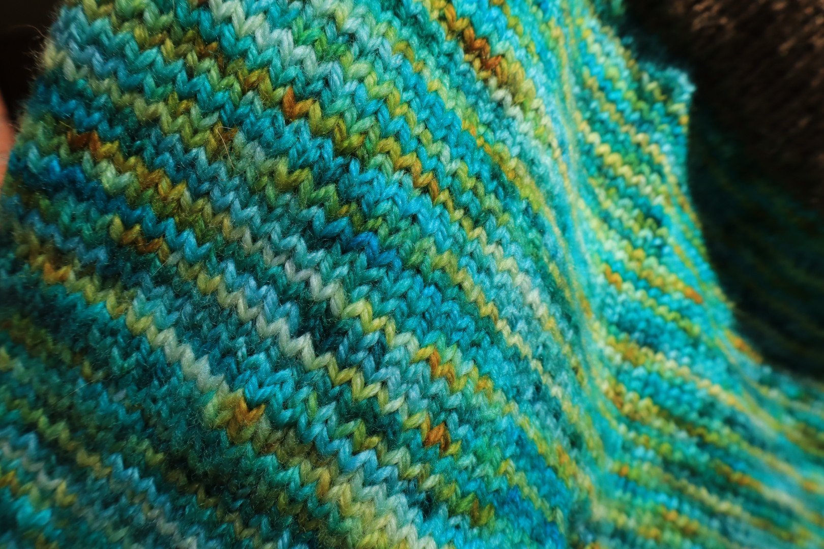 Close-up of colorful knitted fabric with zigzag pattern in shades of blue, green, yellow, and orange.