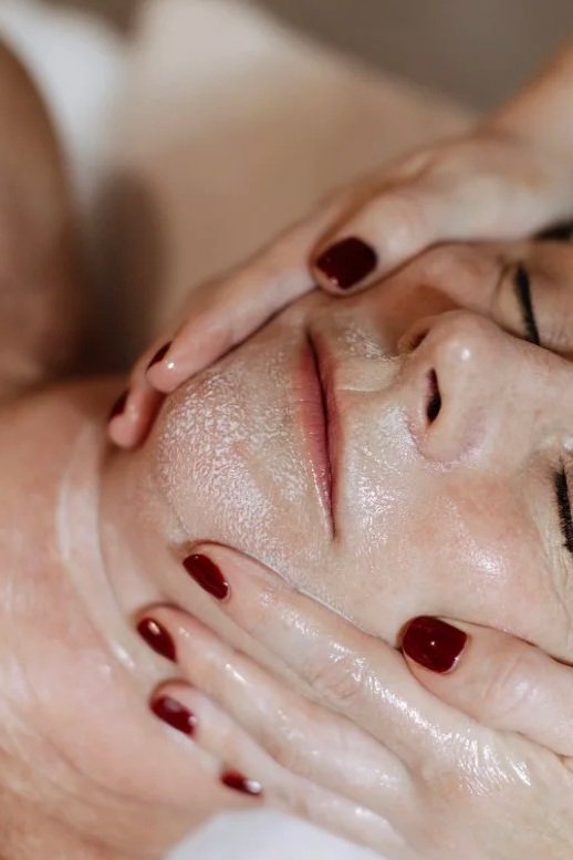 Close-up of a woman receiving a facial massage, with hands gently on her face.