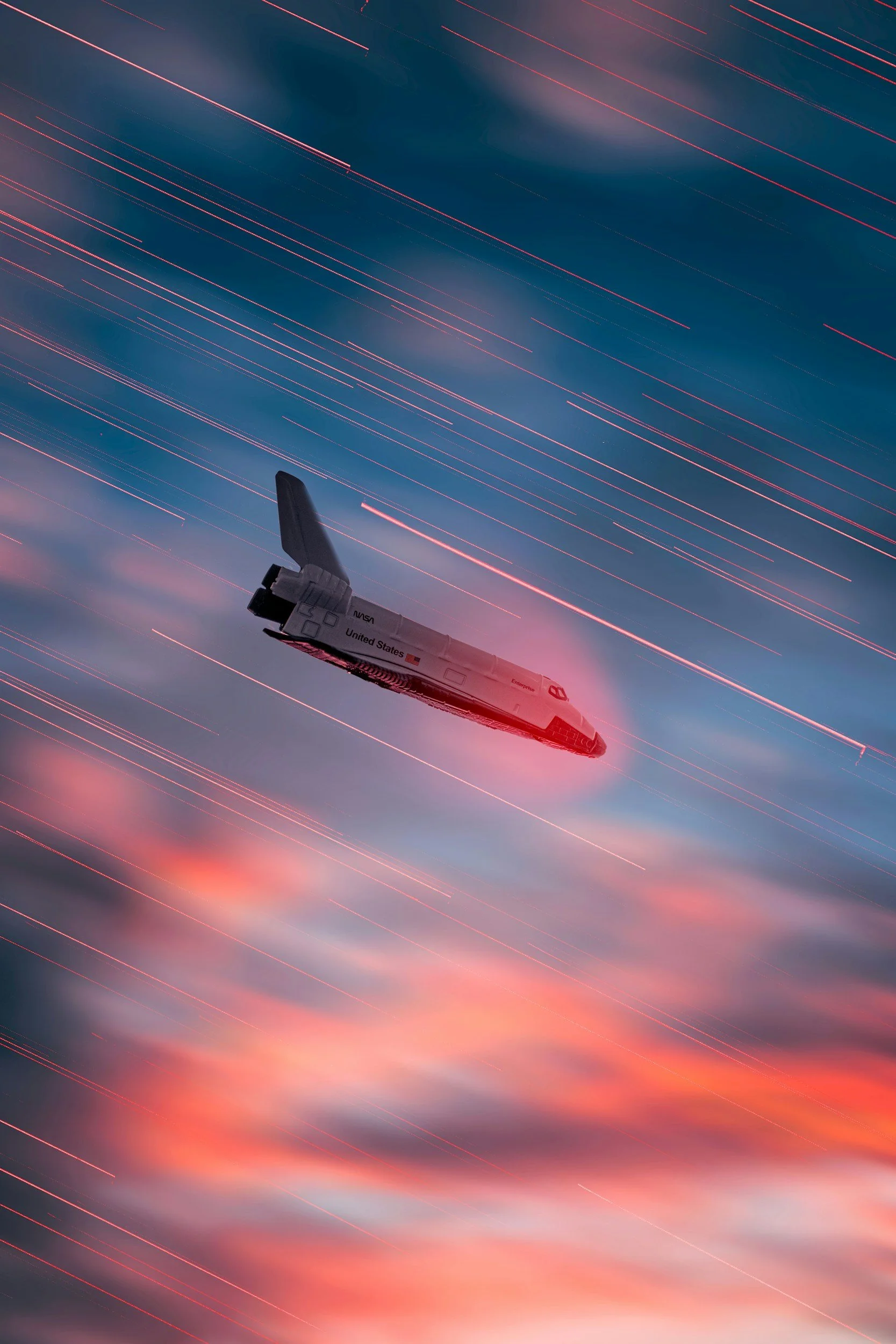 A Space Shuttle with 'United States' and NASA logos on its side, flying through a sky with long streaks of red and pink light, with clouds and a colorful sunset or sunrise in the background.