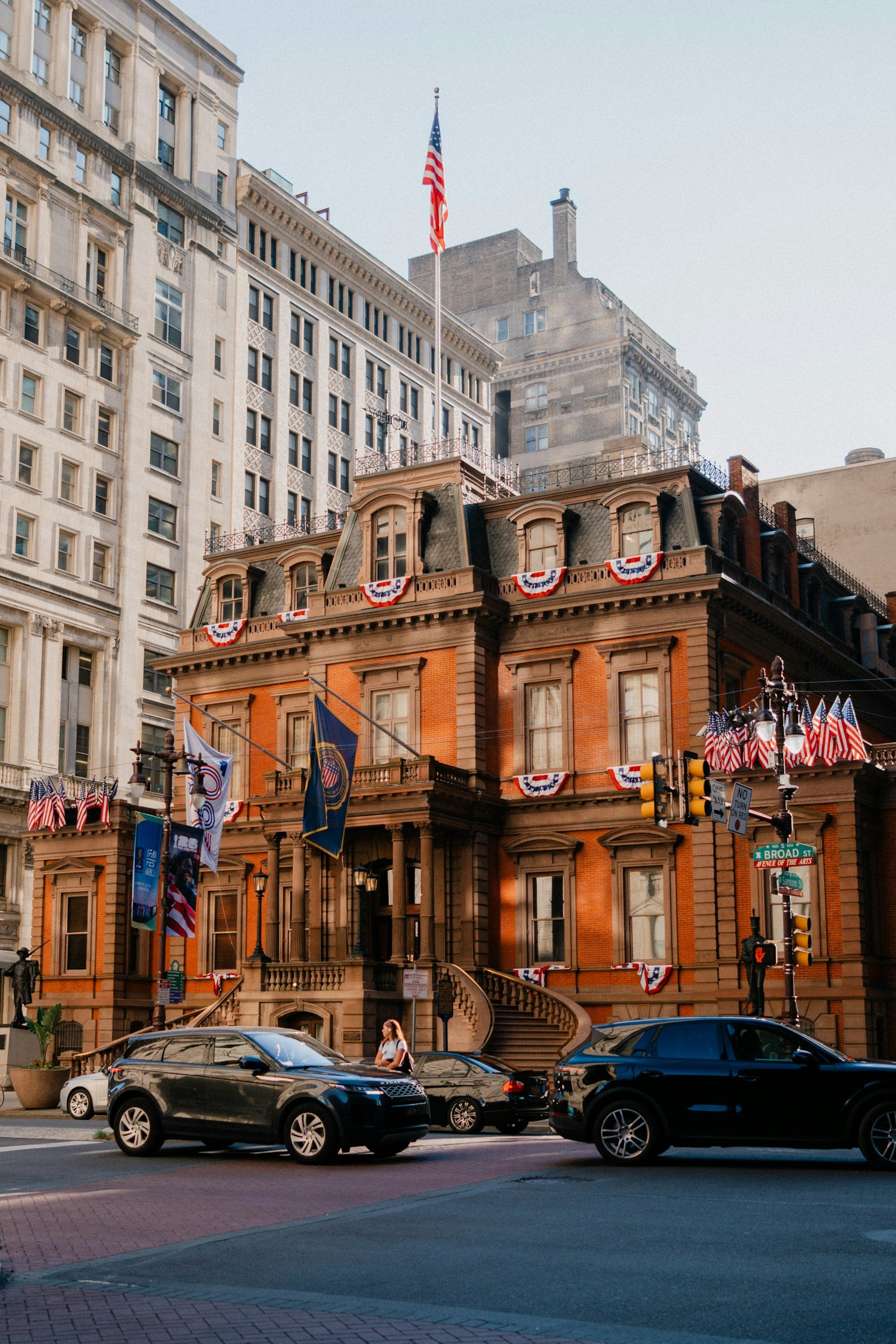 Historic brick building decorated with American flags and patriotic bunting on a city street.