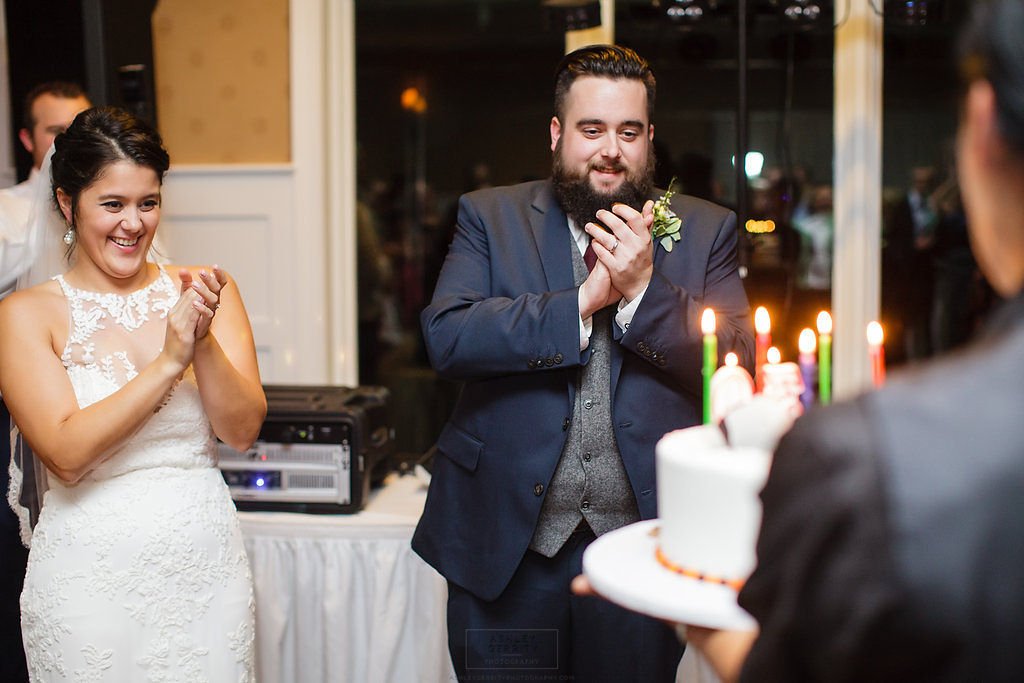 Groom smiling and clapping during a candlelit wedding reception.