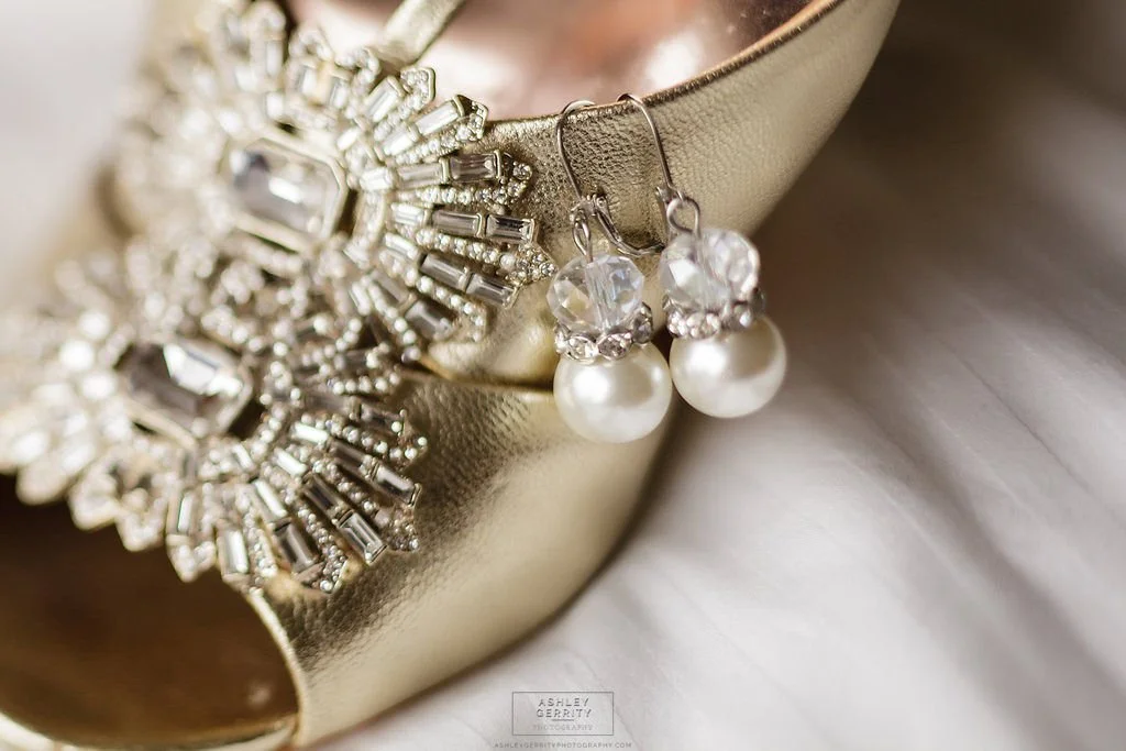 Pearl and crystal bridal earrings displayed on an embellished gold wedding shoe.
