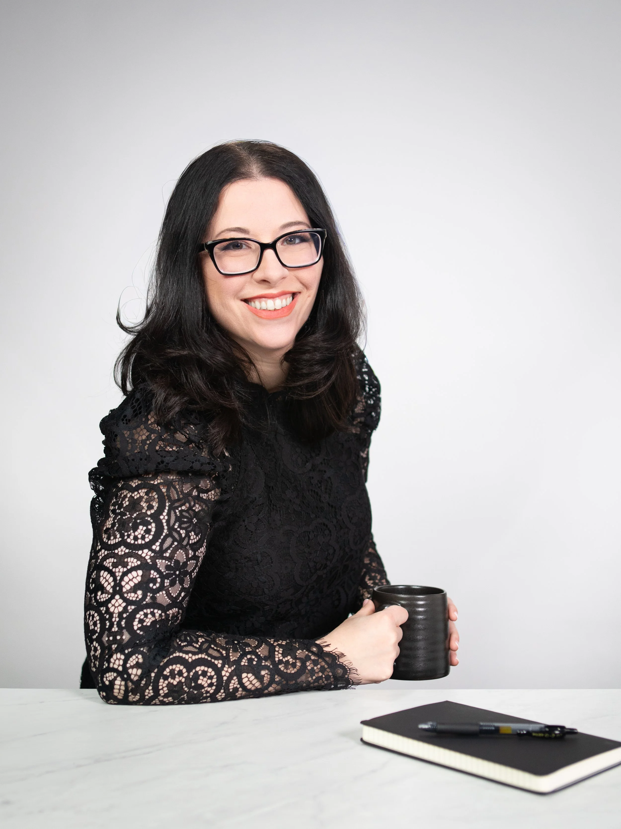 Kiersten, the creative director, smiling while holding a black coffee mug.