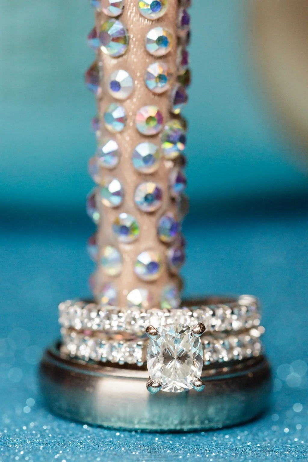 Close-up of a diamond engagement ring and wedding bands displayed against a blue background.