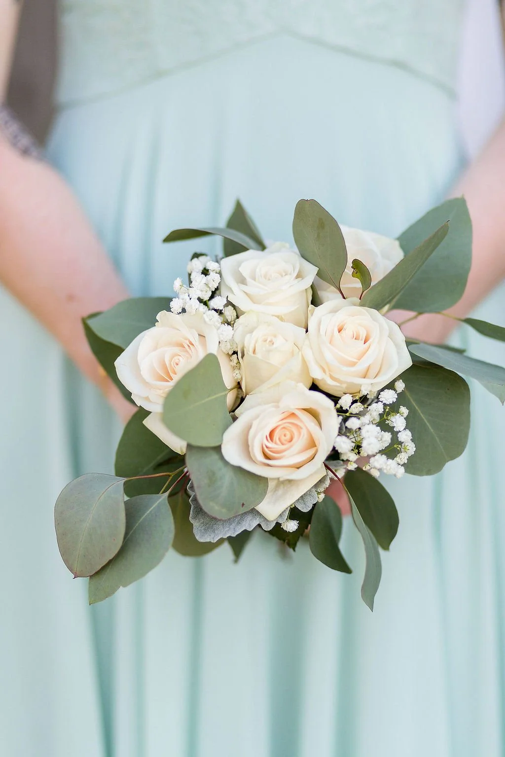 Close-up of a bridal bouquet with ivory roses, baby’s breath, and eucalyptus greenery.