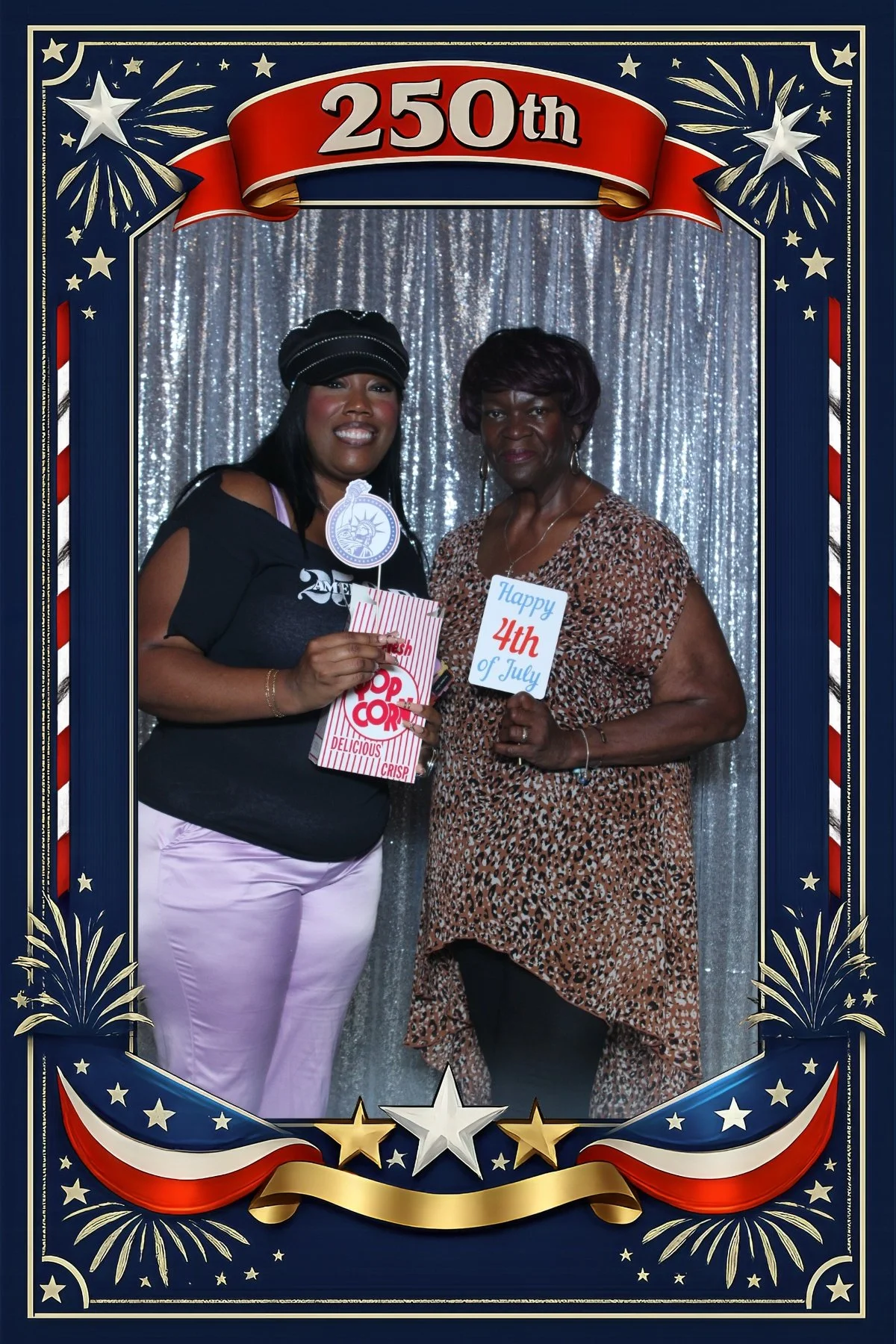 Two women posing with Fourth of July photo booth props in a patriotic 250th anniversary frame.