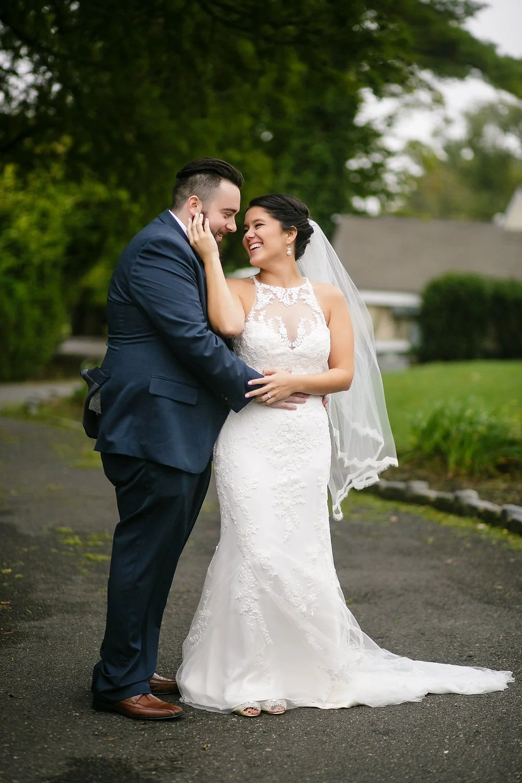 Bride and groom embracing and smiling together outdoors on their wedding day.