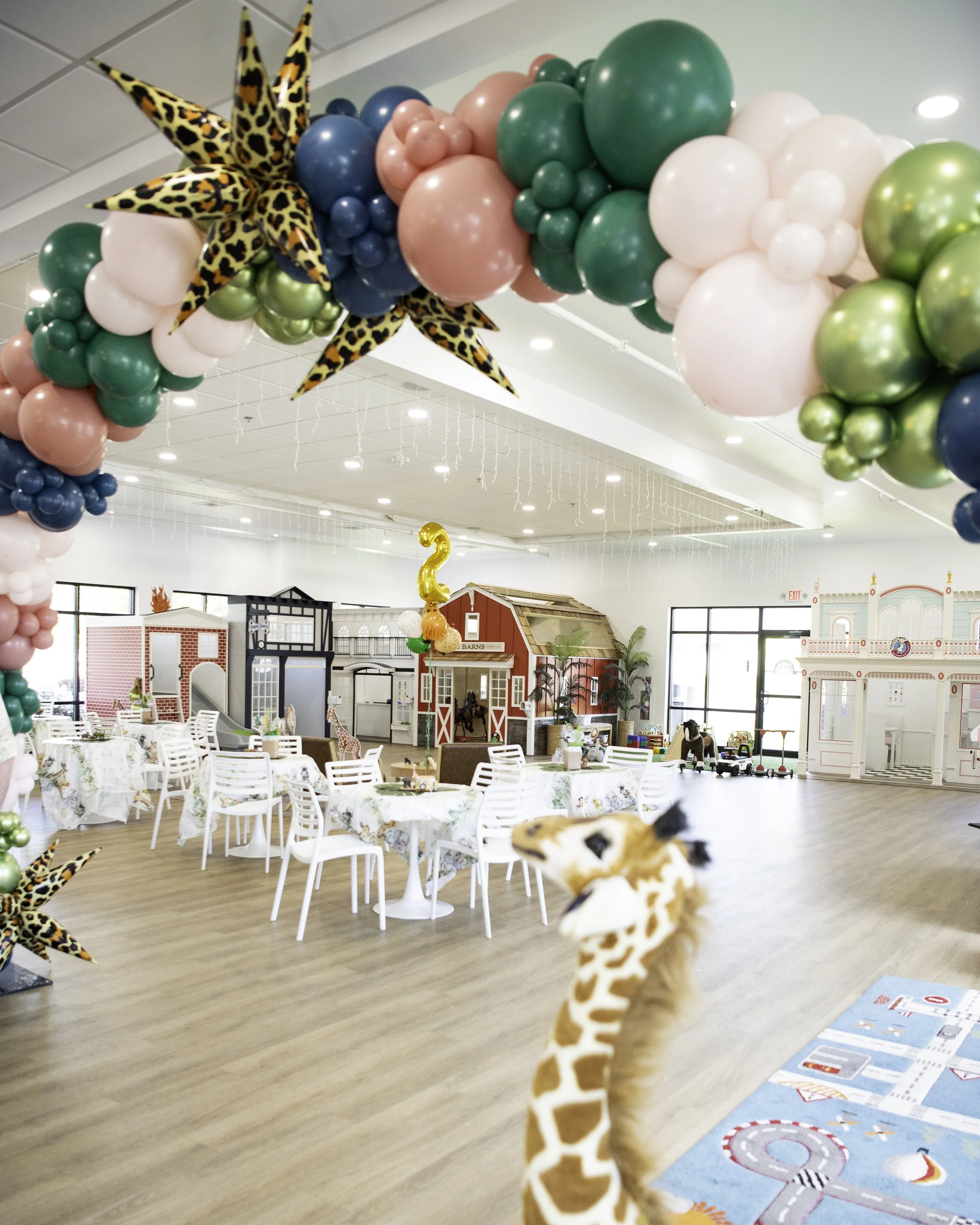 Colorful children’s party venue decorated with balloons, tables, and playful animal decorations.