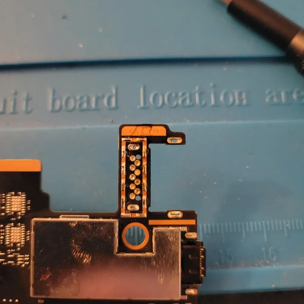 Close-up of electronic circuit board with small components on a light blue surface.