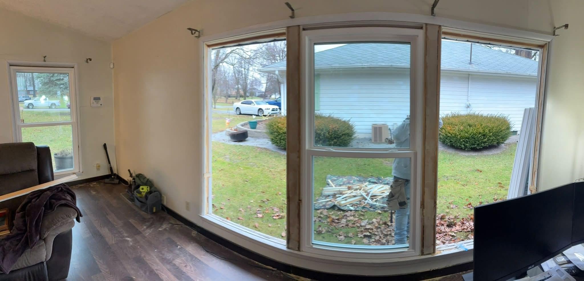Construction worker installing new window in a house, seen from inside the room.