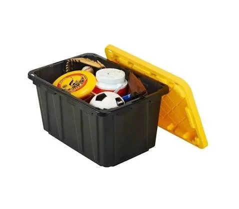 A black and yellow storage case with its yellow lid open, containing various objects including a soccer ball, a container of food, and other miscellaneous items.
