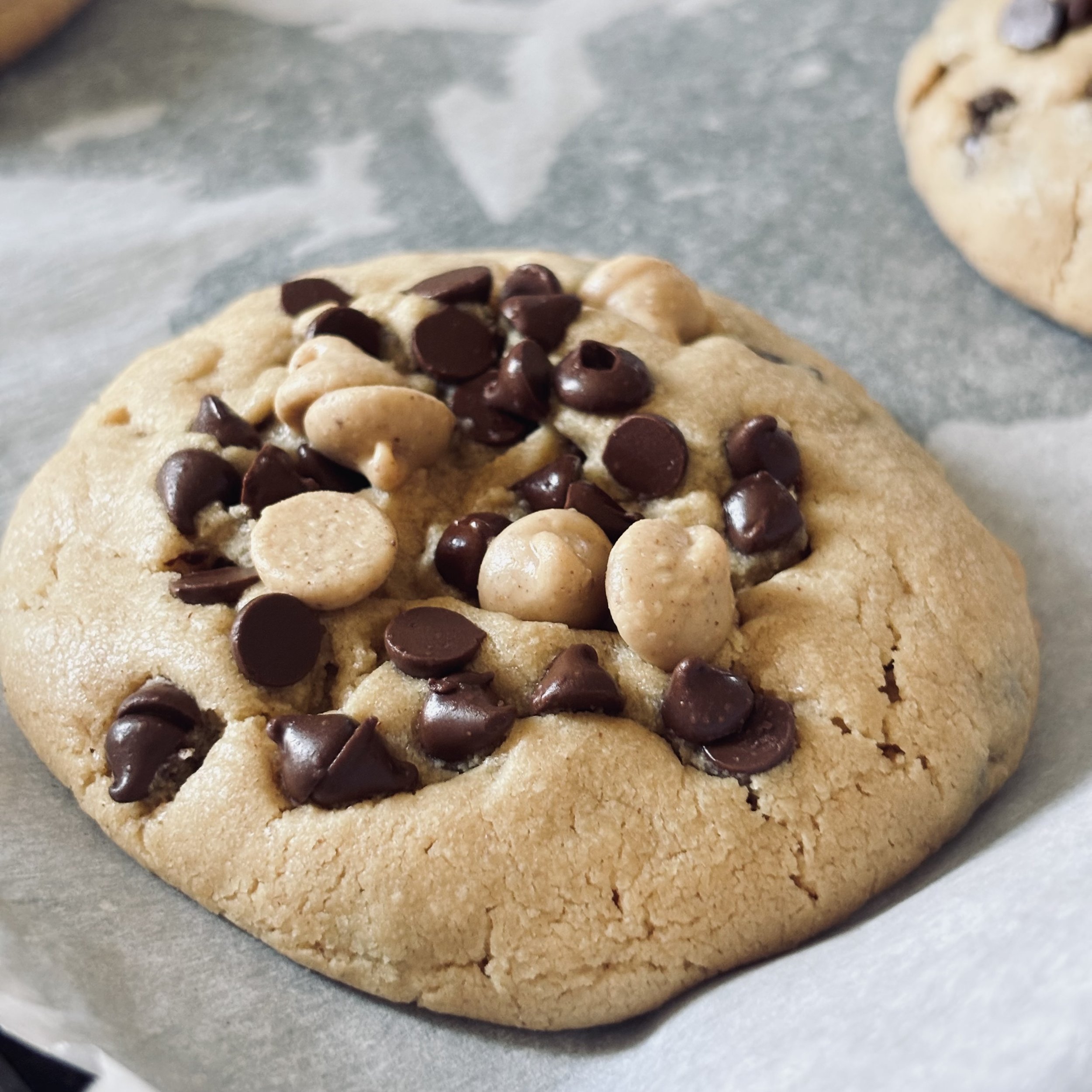 Close-up of a chocolate chip cookie dough ball on a sheet of parchment paper.
