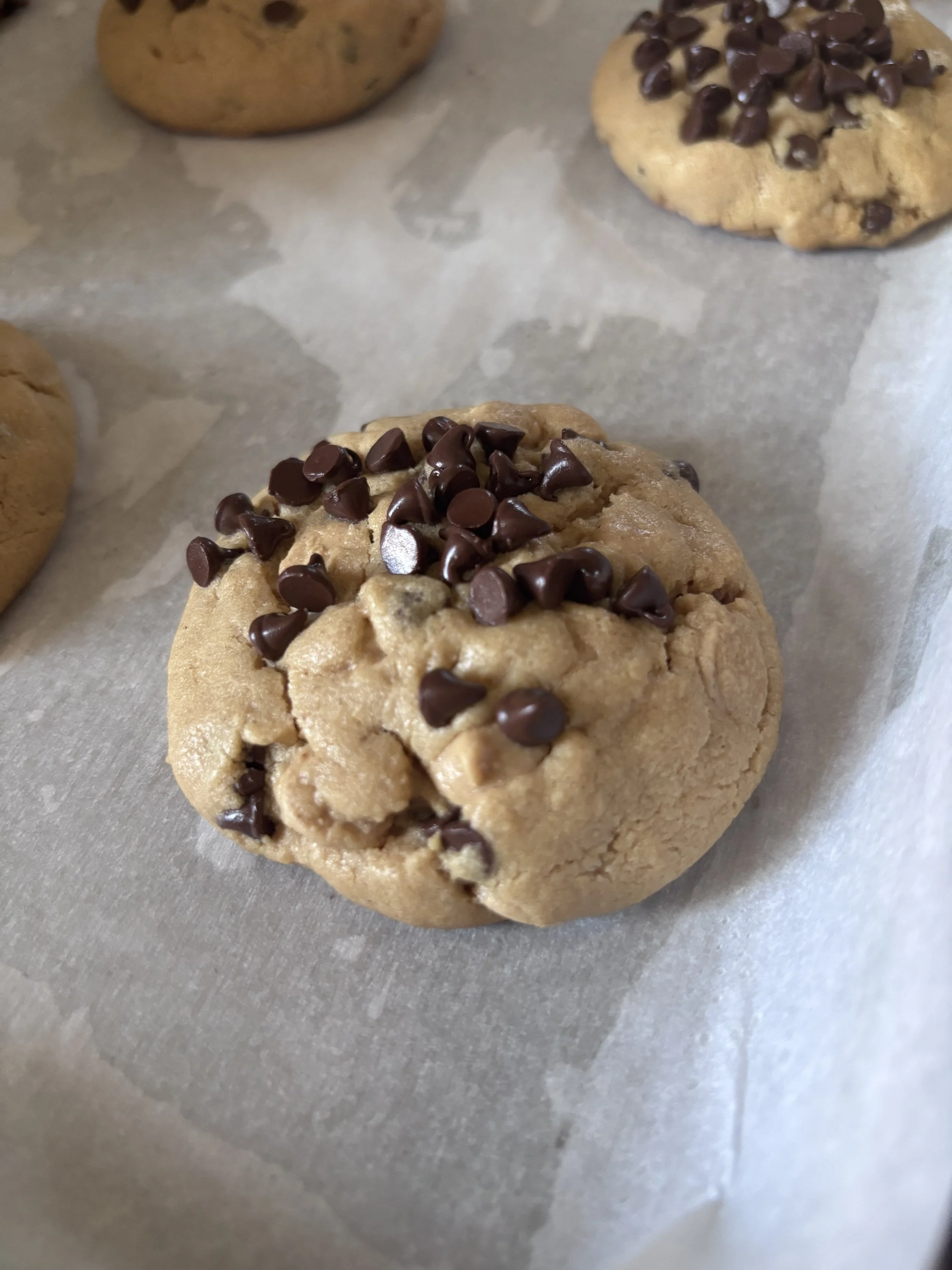 Close-up of chocolate chip cookies on a baking sheet lined with parchment paper.
