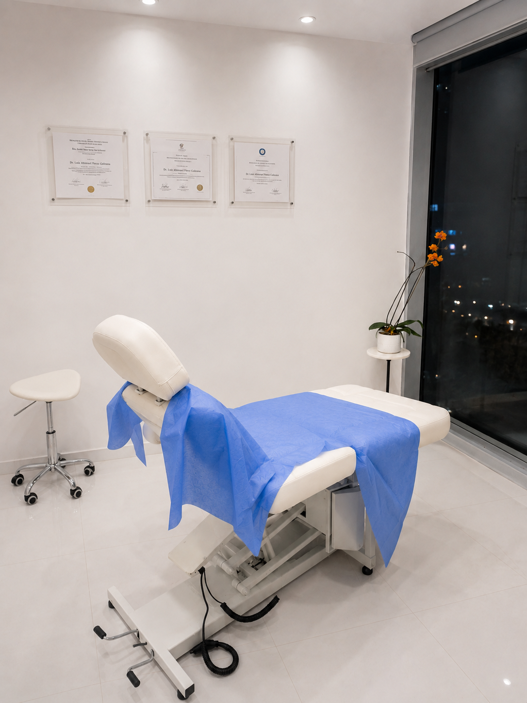 Consulta médica o clínica, camilla con cubrebocas azul, certificados en la pared, florero con planta en la esquina y ventana de cristal con vista nocturna.