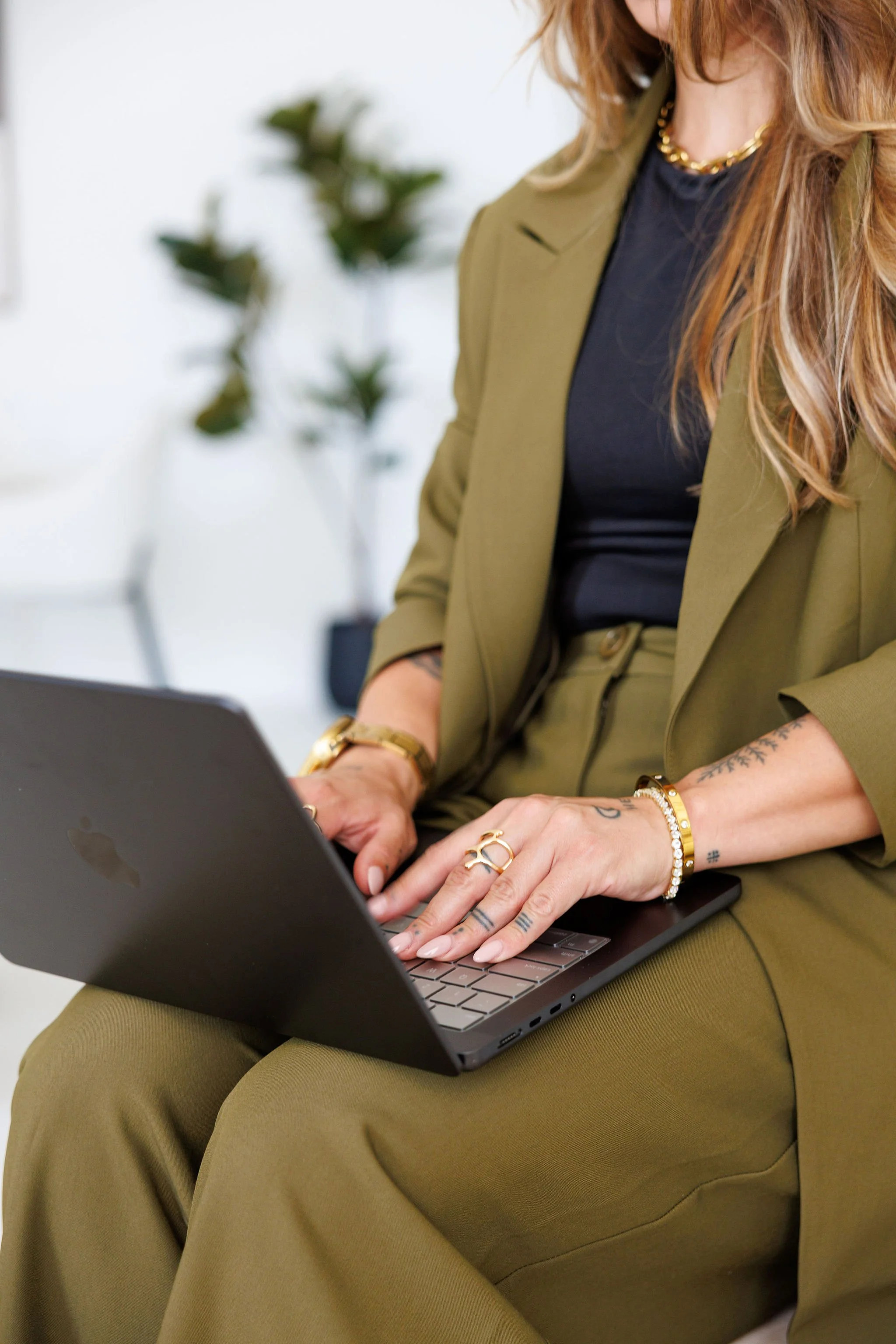 Woman dressed in a green suit working on a laptop in an office environment.