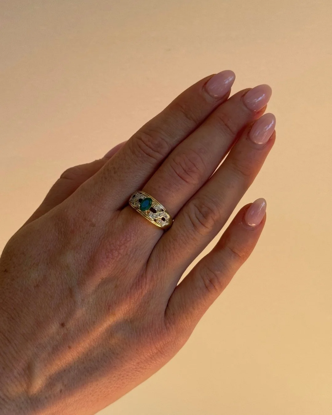 Close-up of hand wearing a vintage 10ct gold emerald and diamond ring - Vallora Vintage
