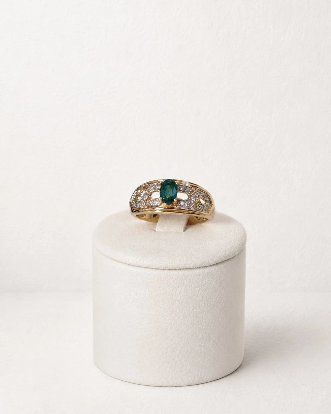 Close-up side view of vintage 10ct gold ring with emerald and diamond scrollwork setting - Vallora Vintage