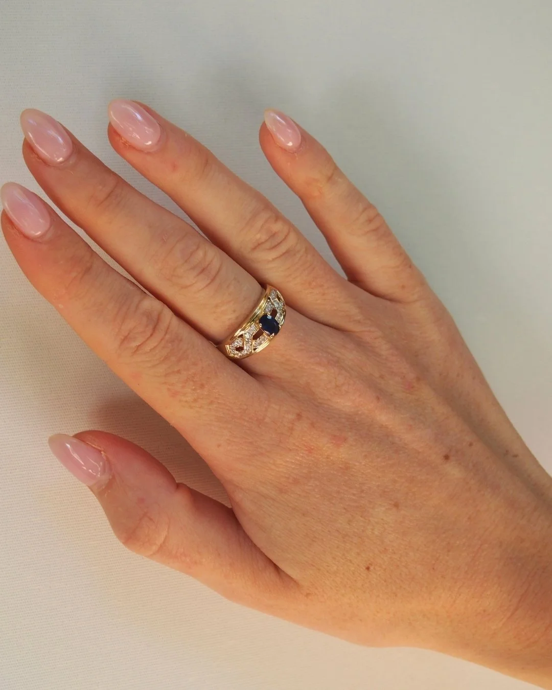 Woman wearing a vintage 10ct gold sapphire and diamond ring on her finger - Vallora Vintage
