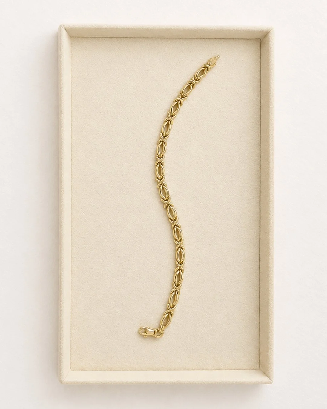 Solid gold chain bracelet with a decorative textured link design laid in a jewelry box