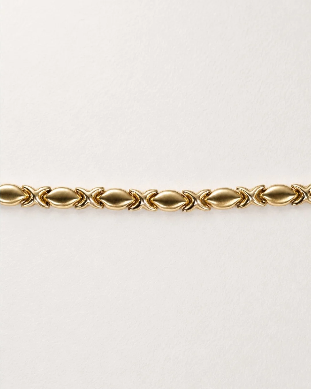 Macro close-up of the solid gold bracelet's textured link pattern