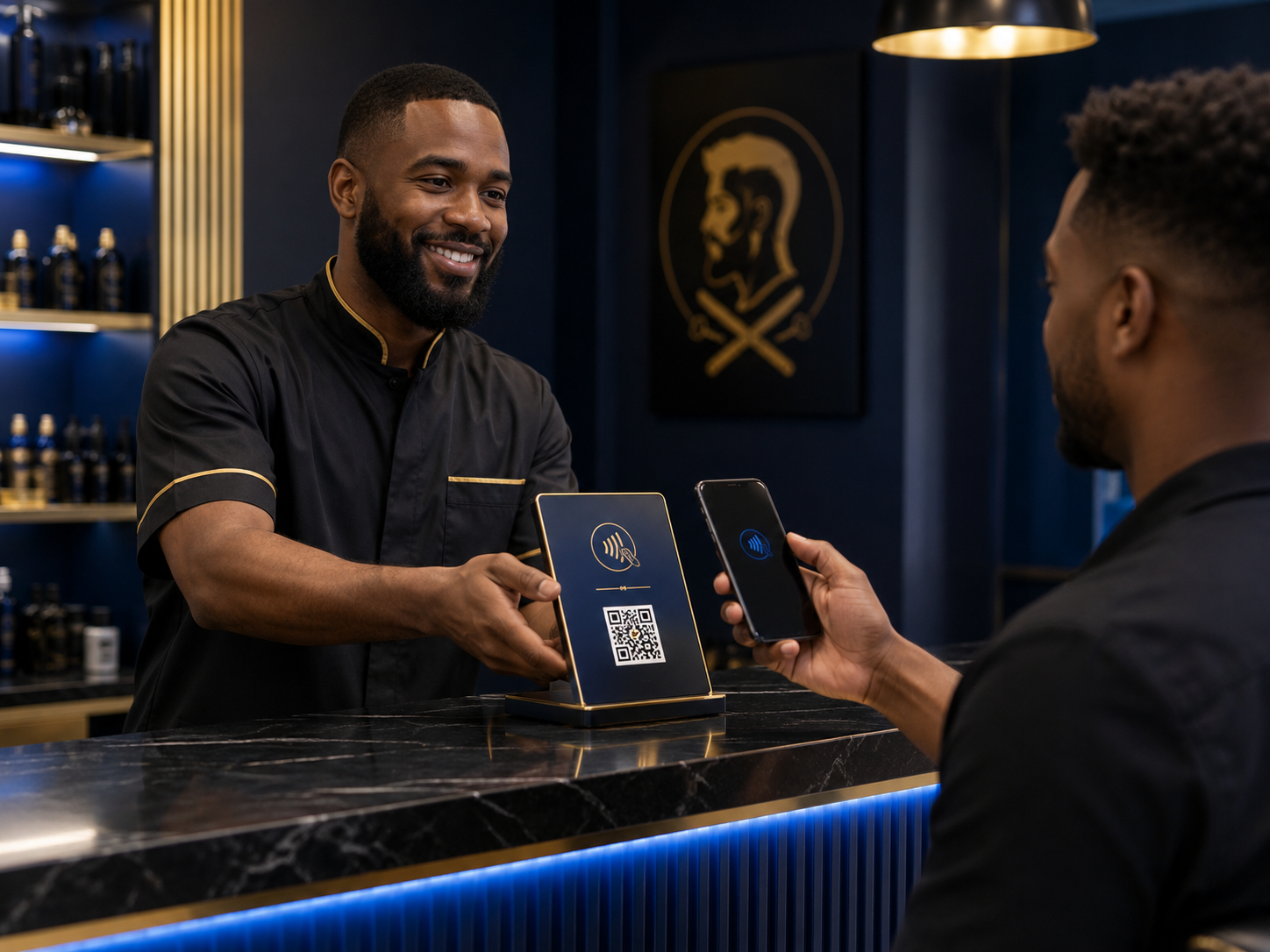 A man at a counter holding a smartphone with a digital payment app, smiling as another man with a beard and black shirt with gold accents holds a tablet displaying a QR code for payment. The scene takes place in a modern, upscale setting with dark blue walls and gold accents, and a framed logo with a face silhouette and crossed scissors in the background.