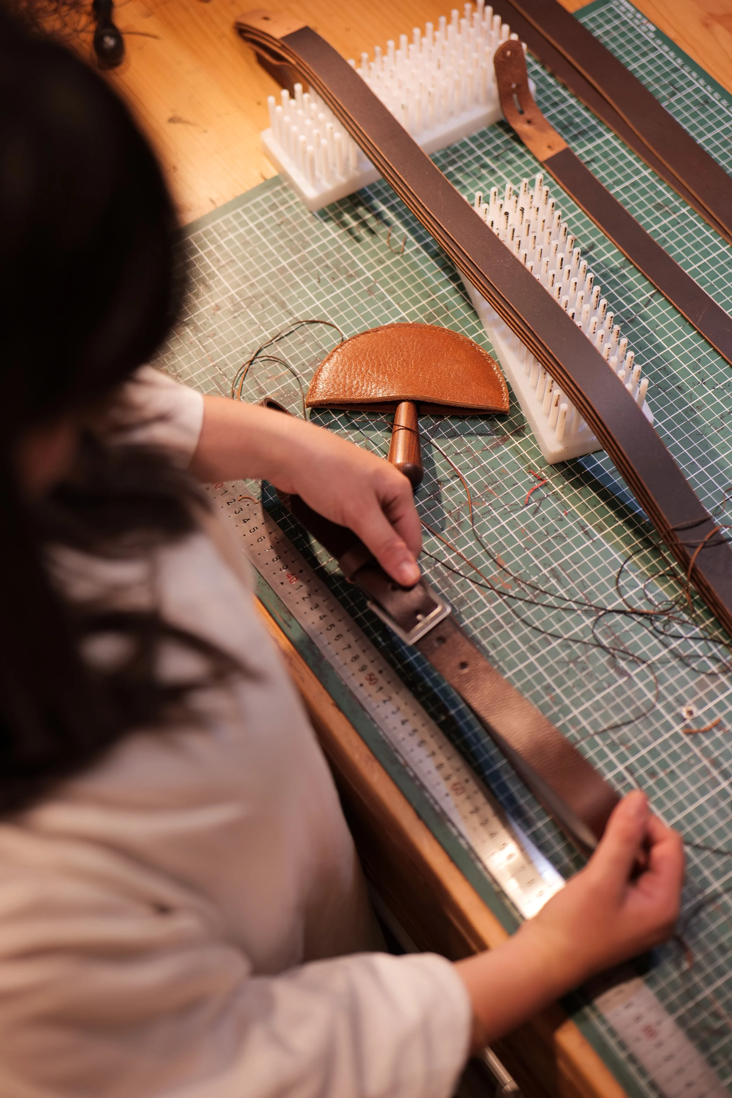 Lauriane travaillant sur Atelier Nappa, équipée d'outils, d'un tapis de découpe et de bandes de cuir.