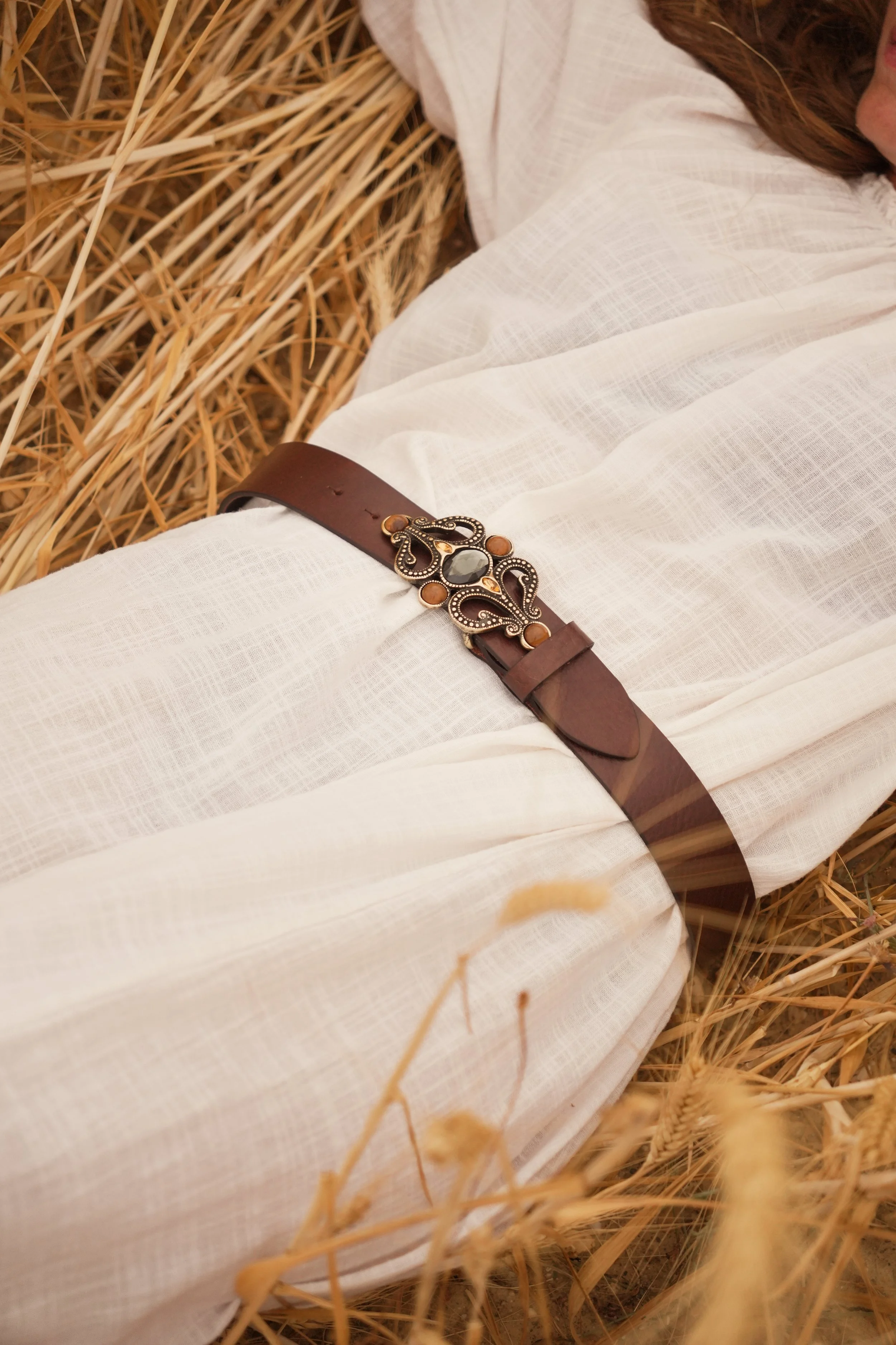 Ceinture en cuir marron avec une boucle bijoux sur une roble blanche