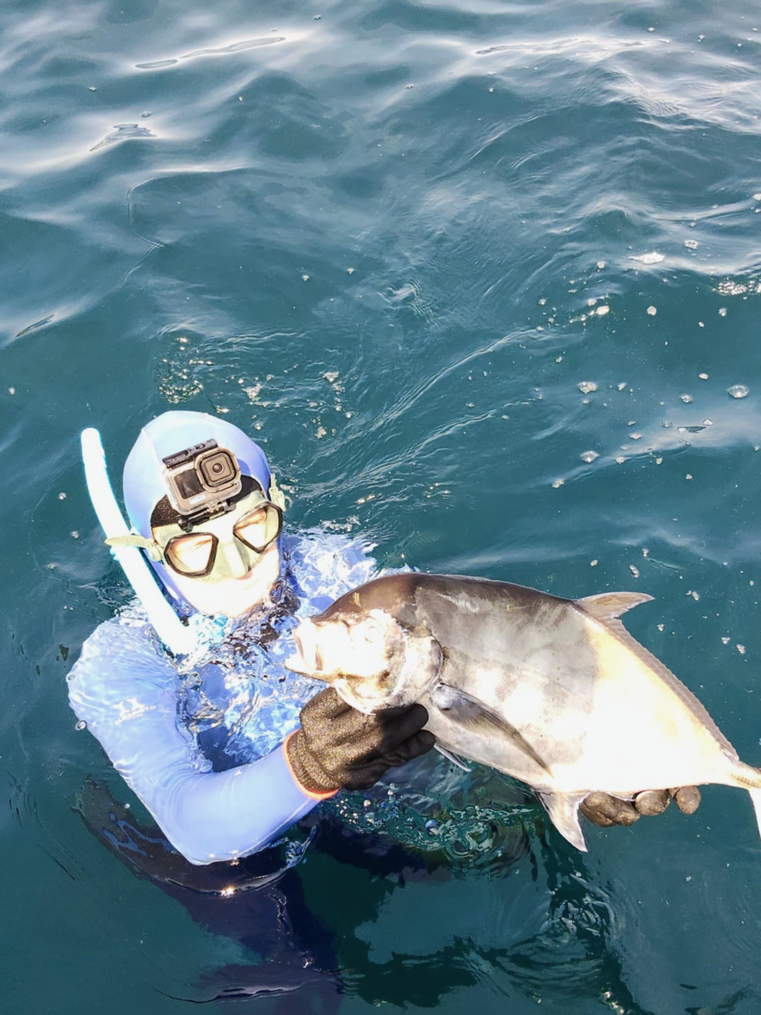 Spearfisher surfacing with a successful catch