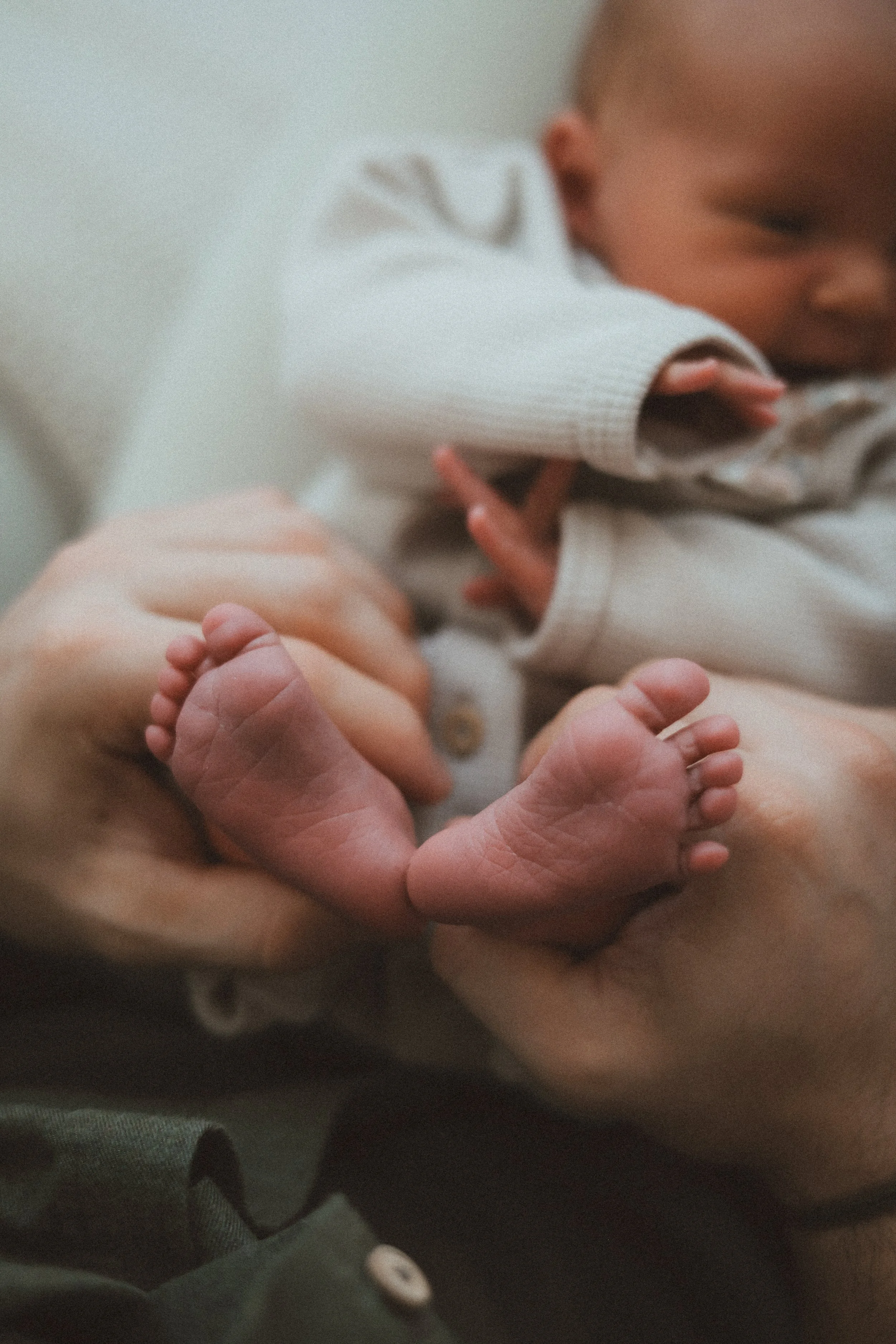 Un bébé tenant la main d'un adulte. L'image est floue, avec un focus sur les petites mains du bébé et de l'adulte.