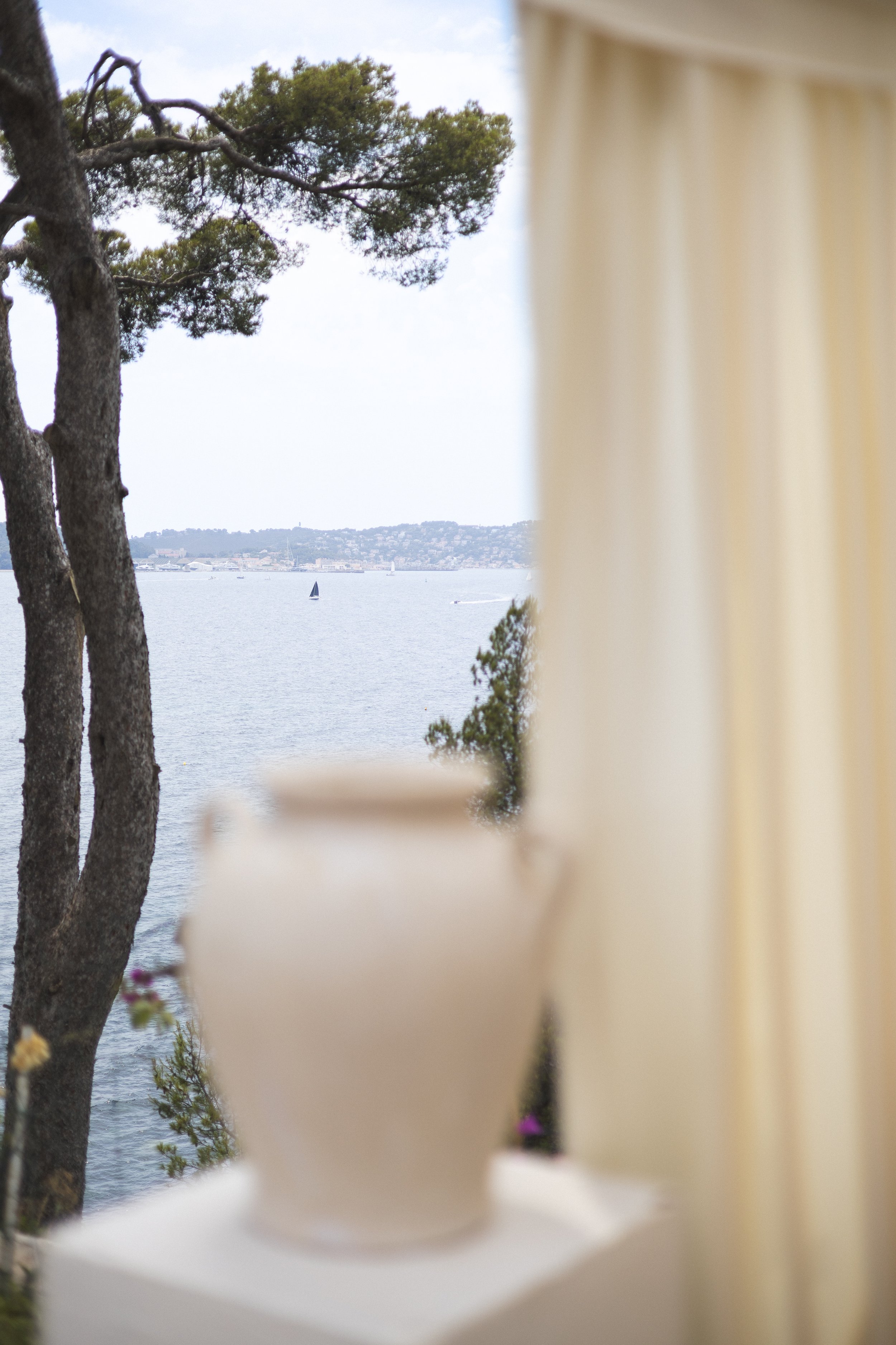 vue d'un plan d'eau avec des arbres et un bateau à voiles, vue partiellement obstruée par une balustrade ou des éléments en bois
