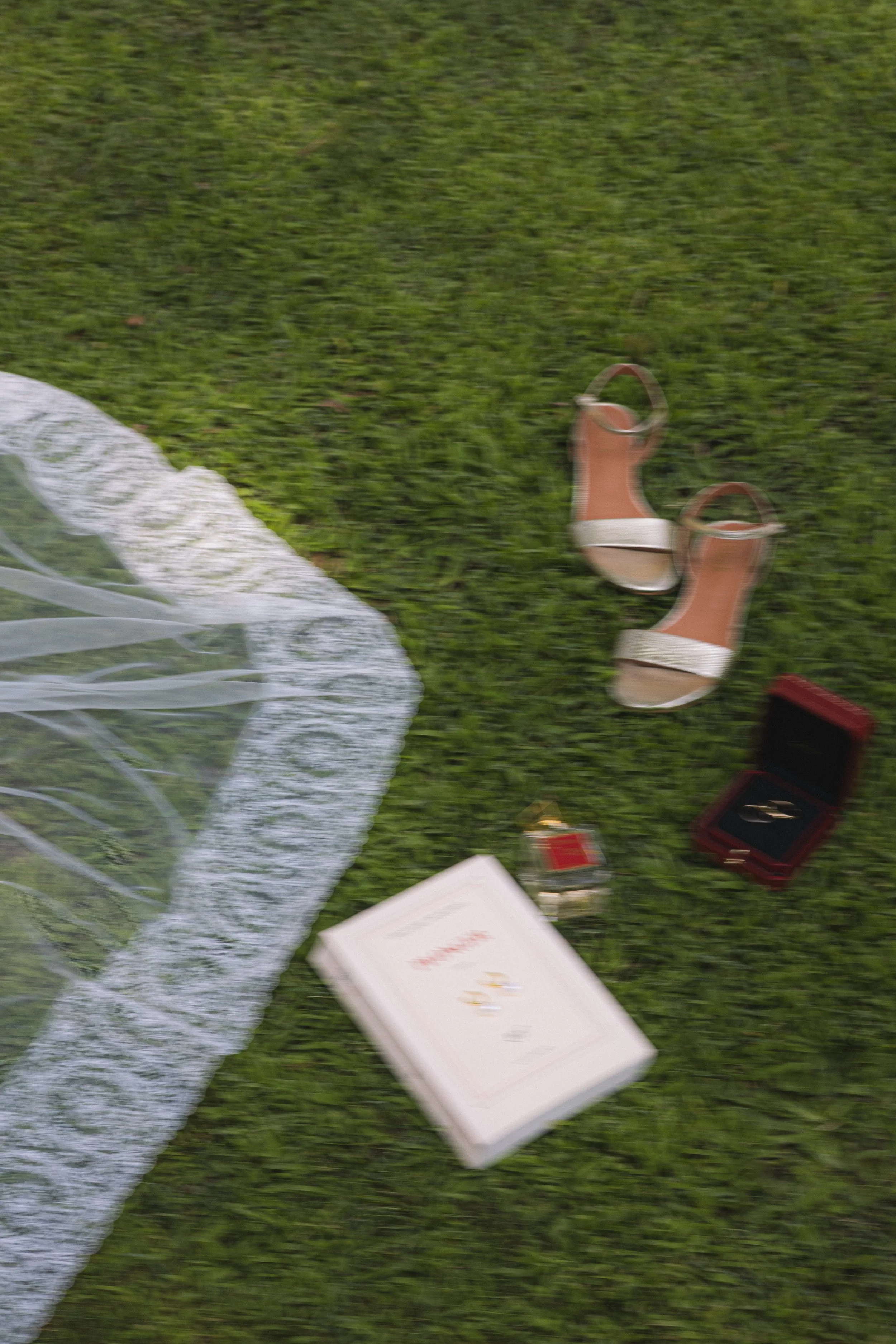 Chaussures à talons en cuir beige, bouquet de fleurs blanches, boîte à bijoux ou coffret rouge, livre ouvert avec texte, petit objet blanc, boîte blanche de médicaments.