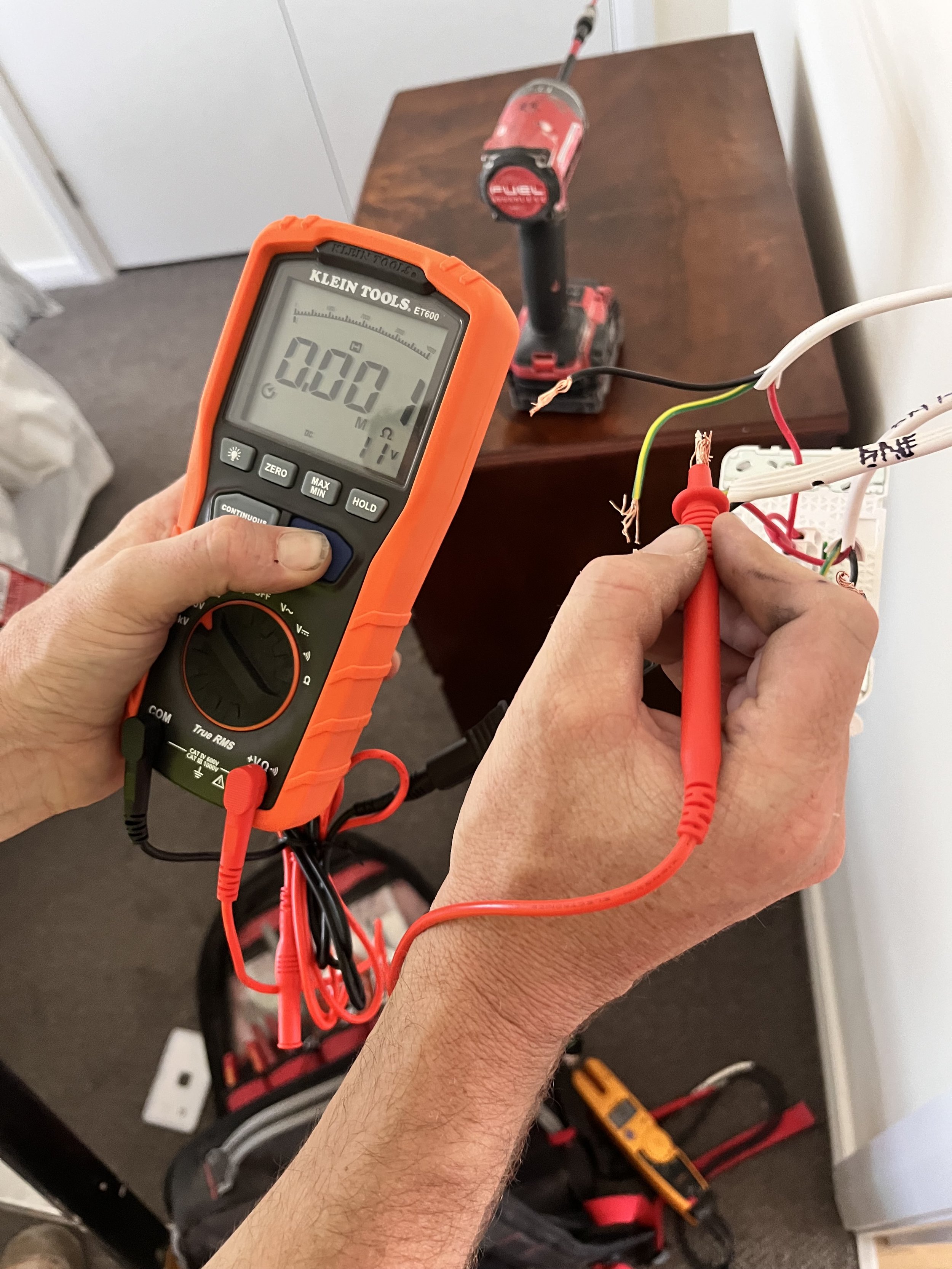 Electrician testing a circuit with a multimeter, Canberra Electric Co