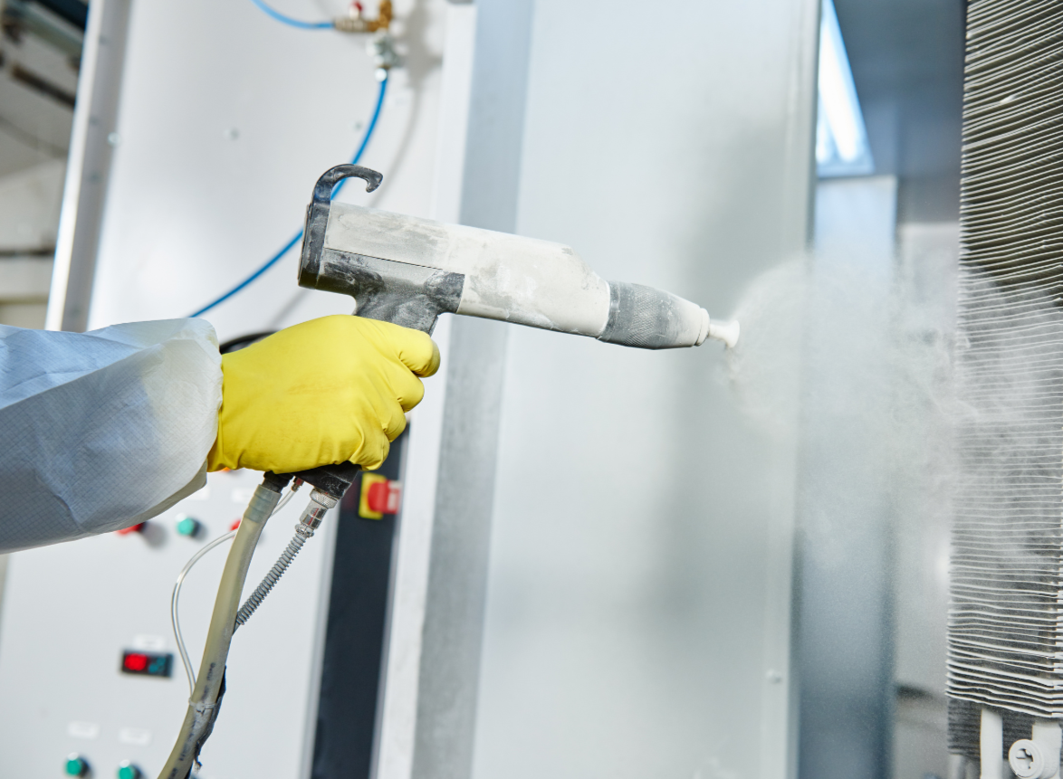 Person mit gelber Gummihandschuhen reinigt eine Maschine mit einem Dampfreiniger, bei der Reinigung entsteht Dampf.