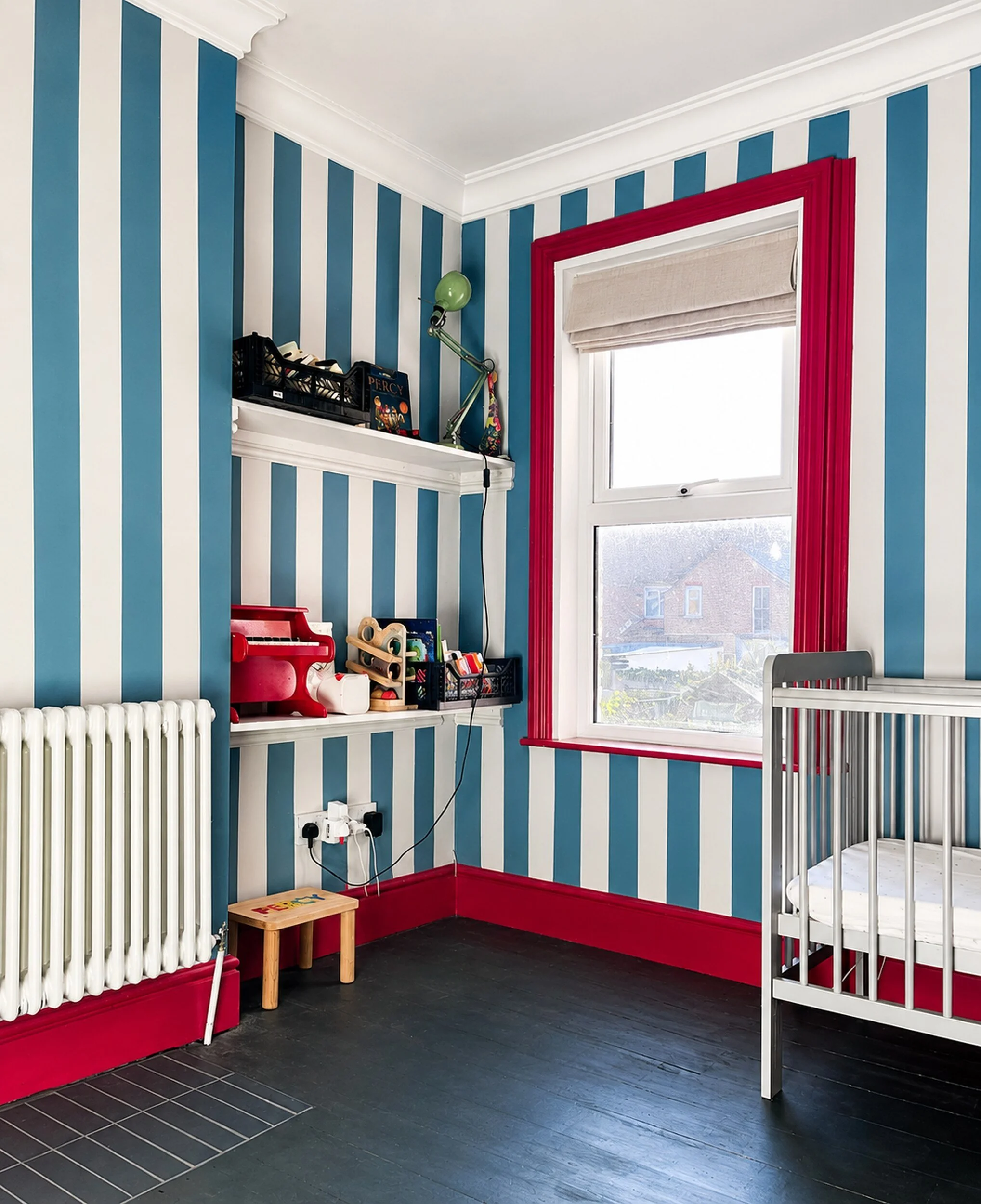Children’s bedroom with hand-painted blue and white wall stripes and contrasting red woodwork.