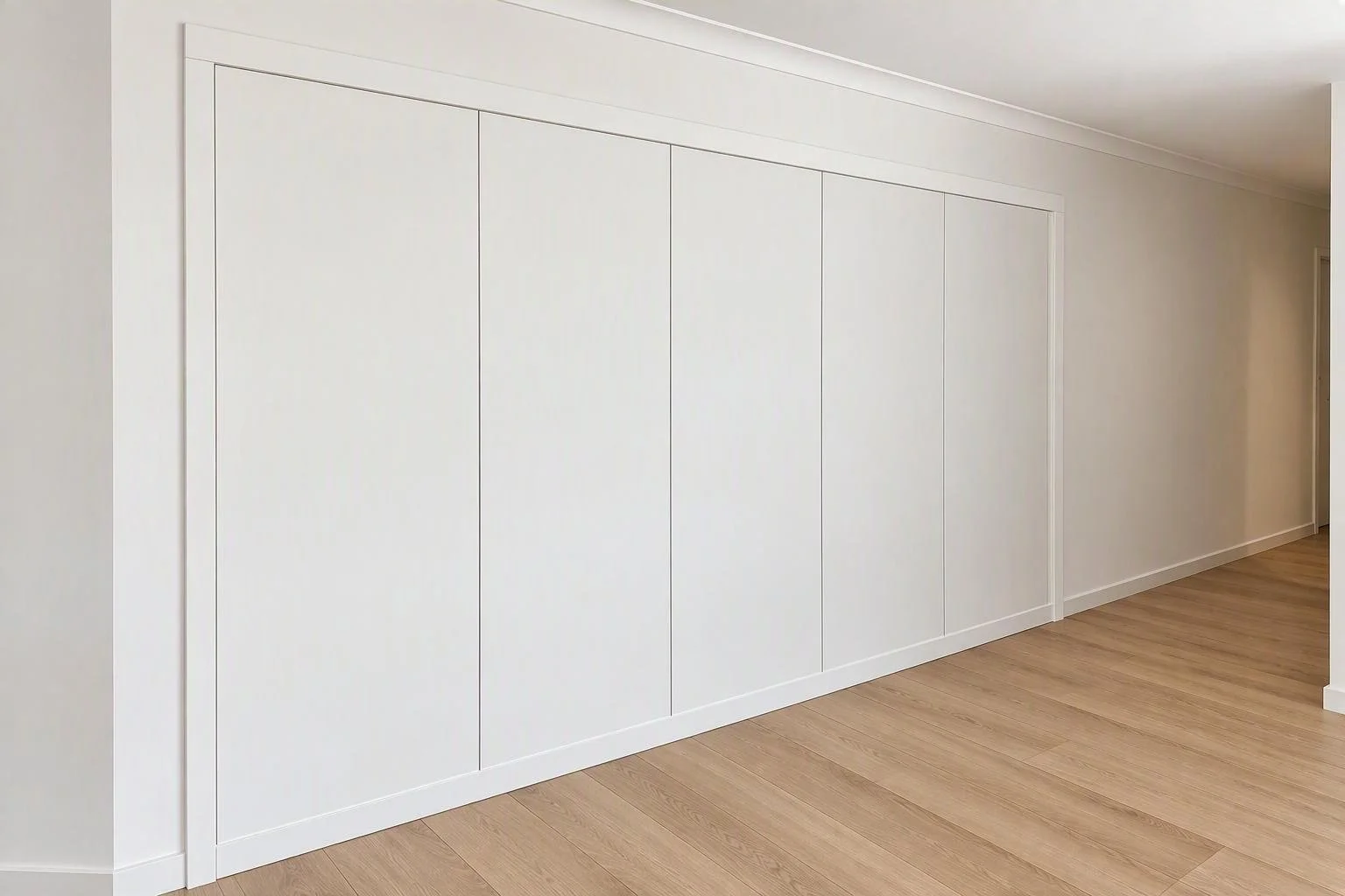 Empty white wall with built-in storage panels and a wooden floor.
