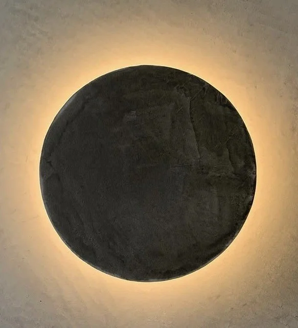 A round, dark object with a glowing edge against a plain wall.