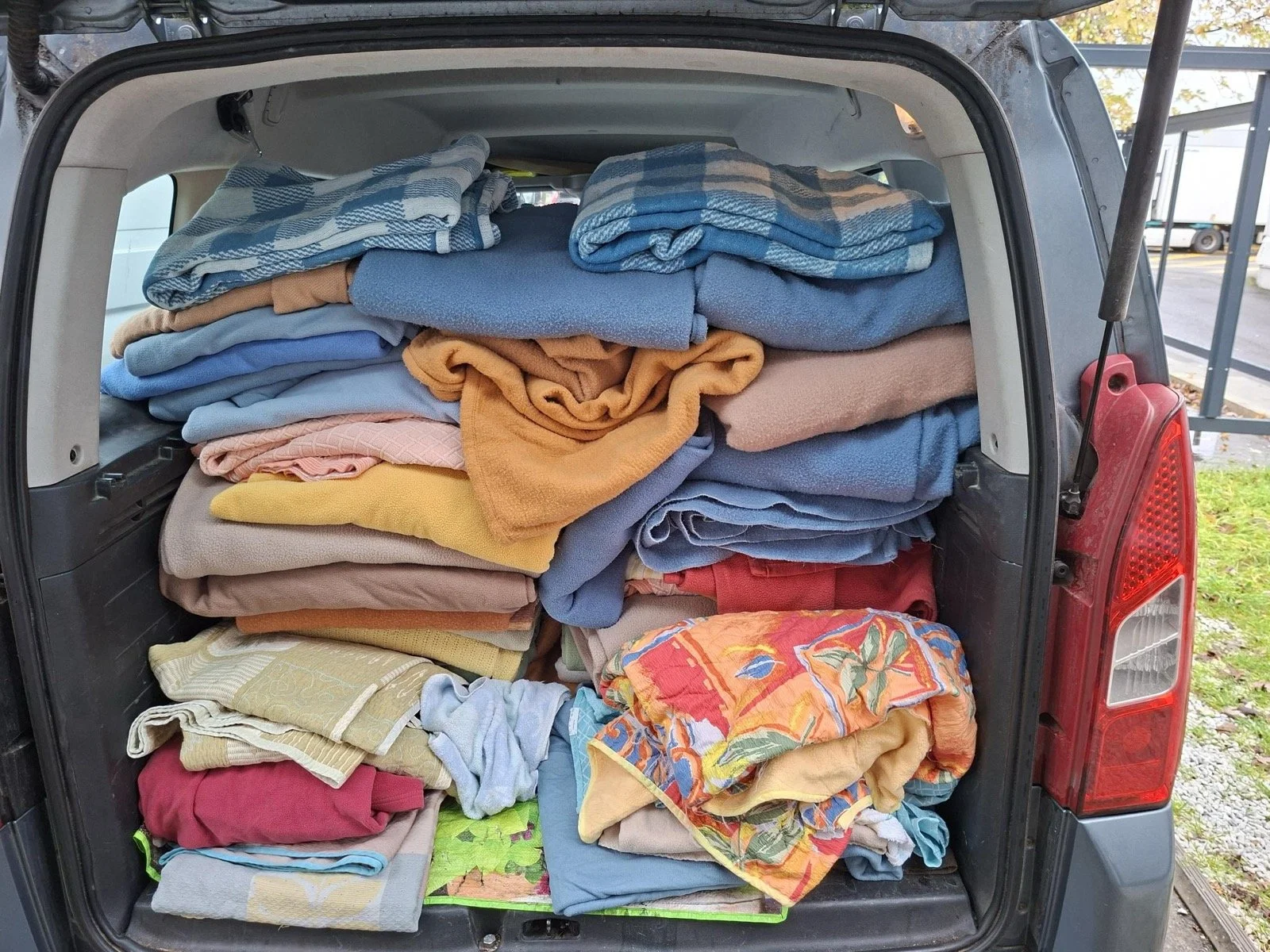 Coffre de voiture rempli de serviettes et de couvertures colorées pliées et empilées.