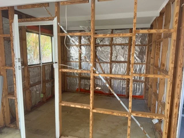 Interior of a room under construction with exposed wooden framing and insulation foil panels on the walls