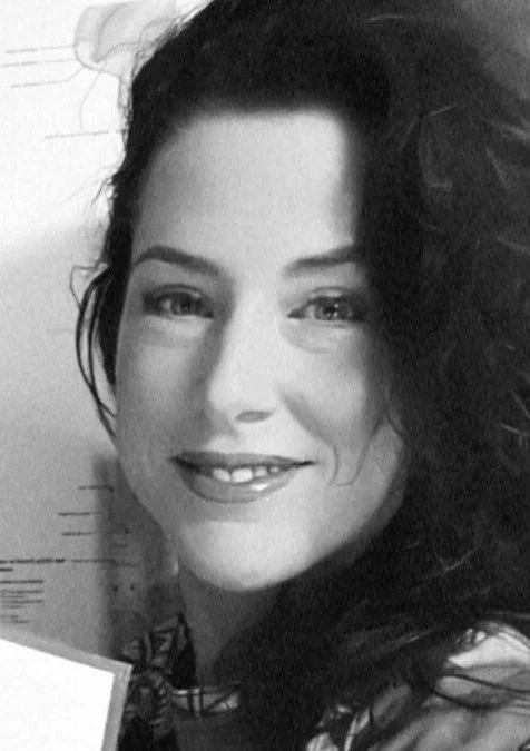 Een zwarte en witte foto van een glimlachende vrouw met lang, golvend haar.