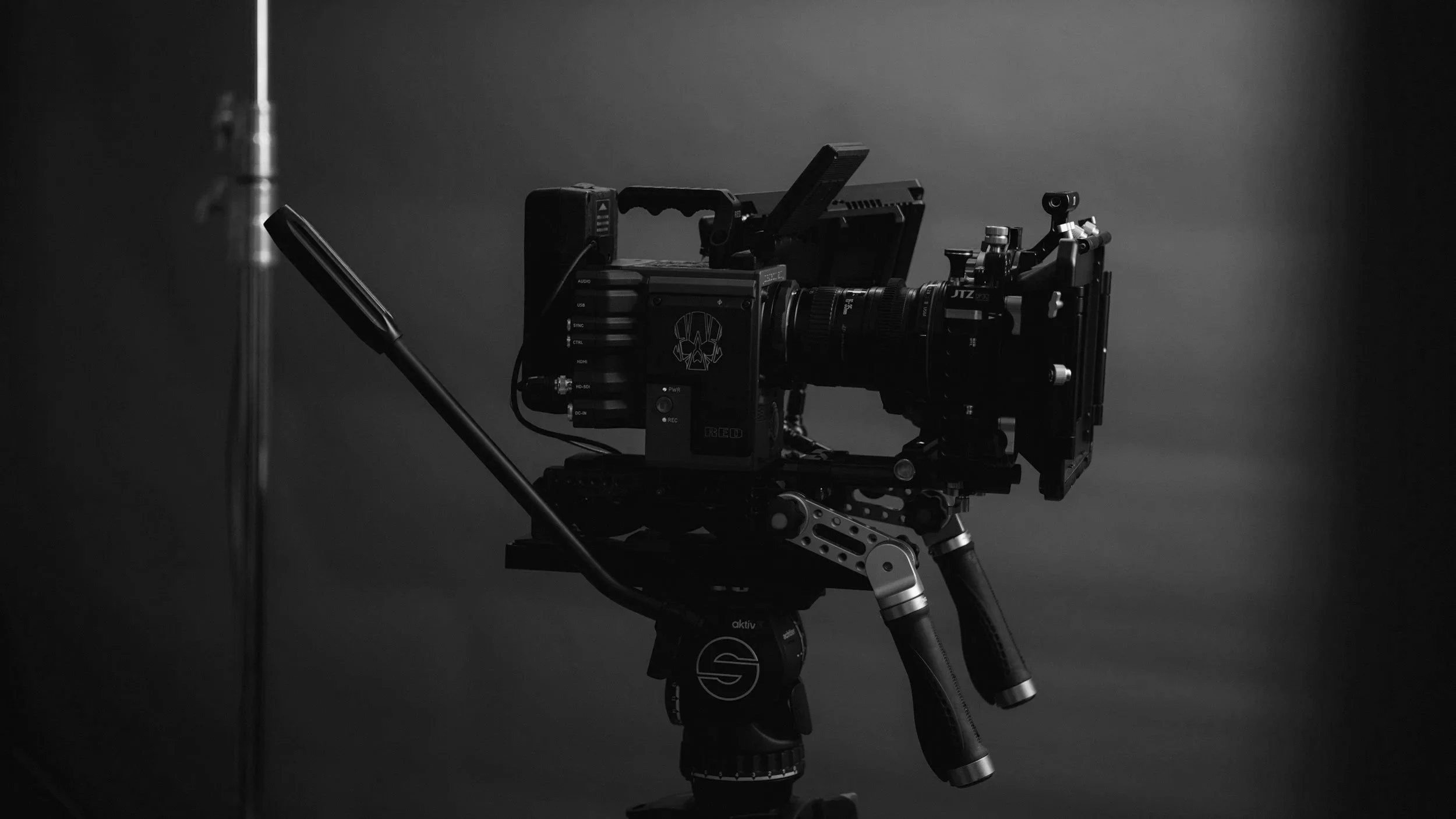 A professional camera mounted on a tripod in a studio setting with a dark background.