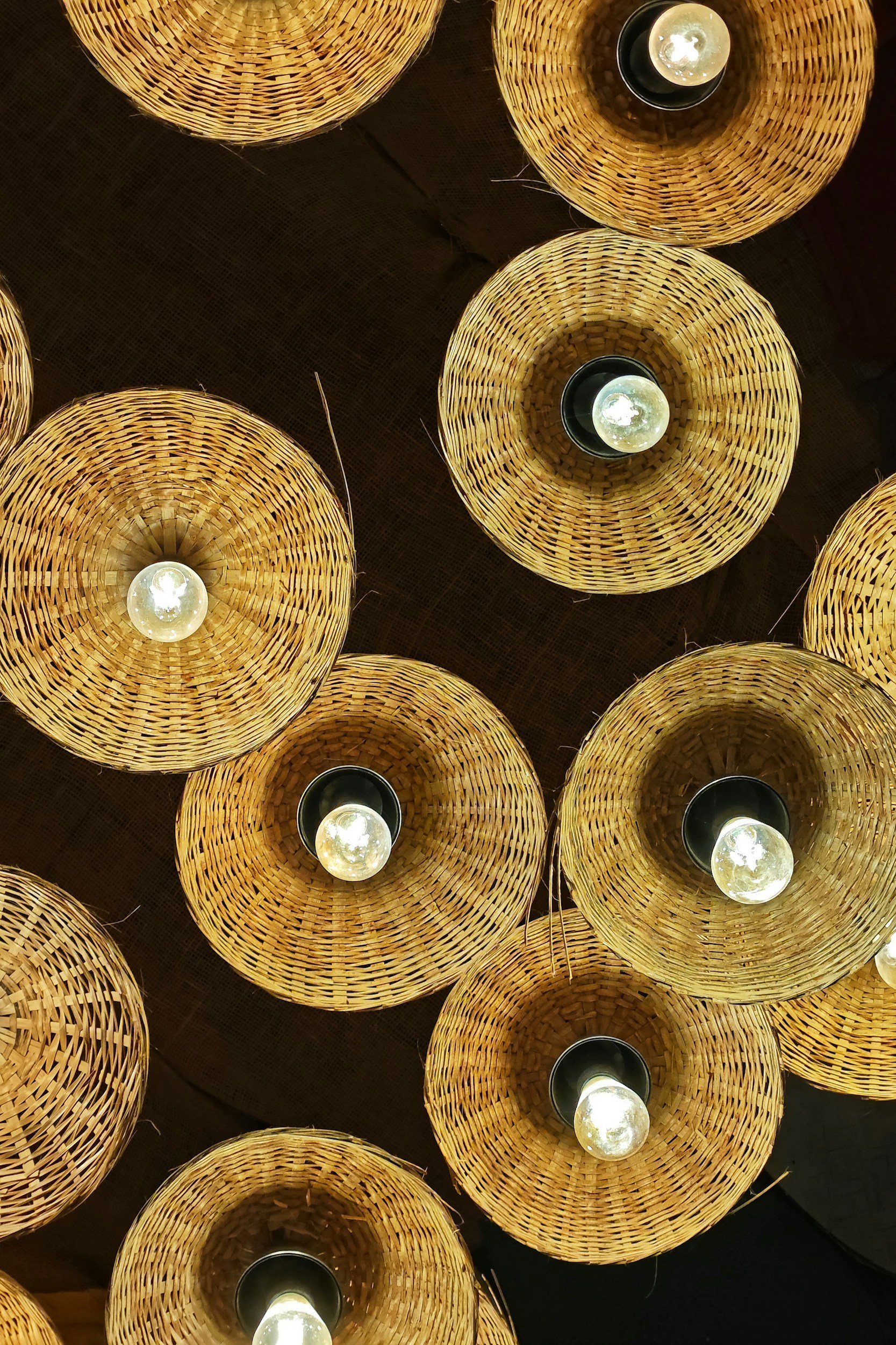 Multiple wicker pendant lights with bulbs hanging inside.