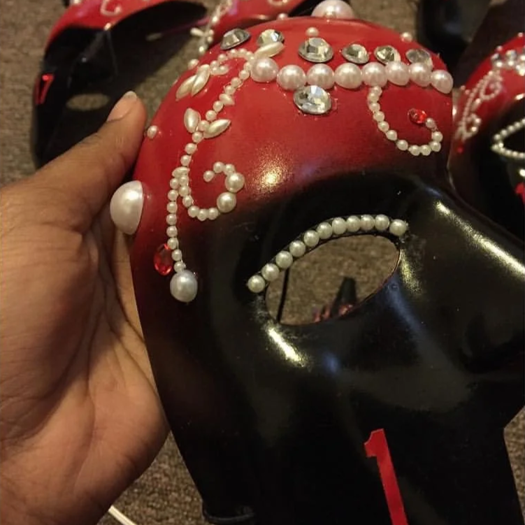 Decorative black and red masquerade mask adorned with pearls and rhinestones