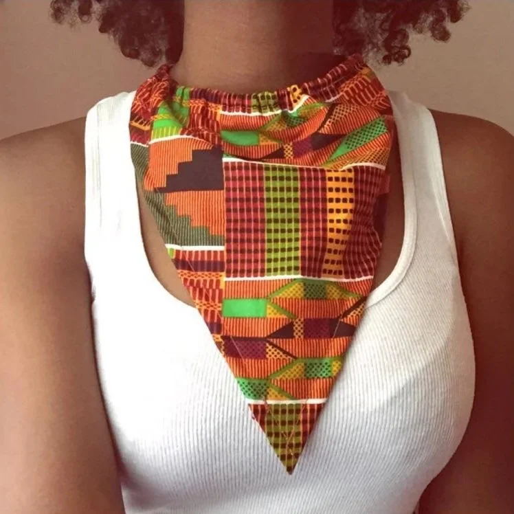 A woman wearing a white tank top with a colorful, patterned fabric resembling a bandana around her neck.